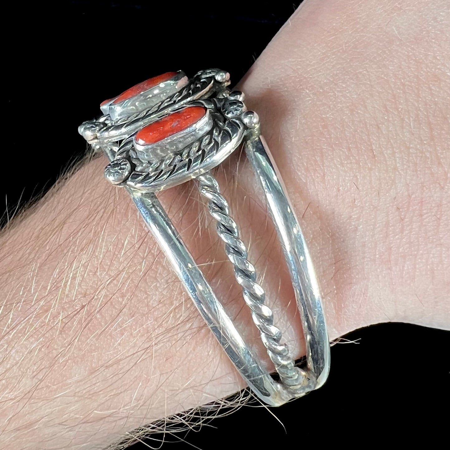 A sterling silver cuff bracelet set with polished coral branches handmade by Navajo artist, Delbert Chatter.