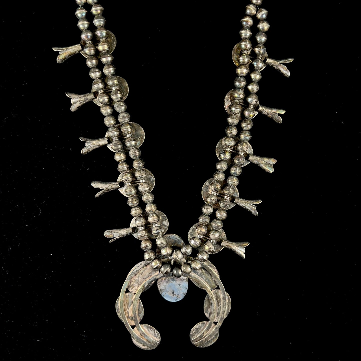 A silver Navajo style unisex squash blossom necklace set with oval cut Sleeping Beauty turquoise stones.
