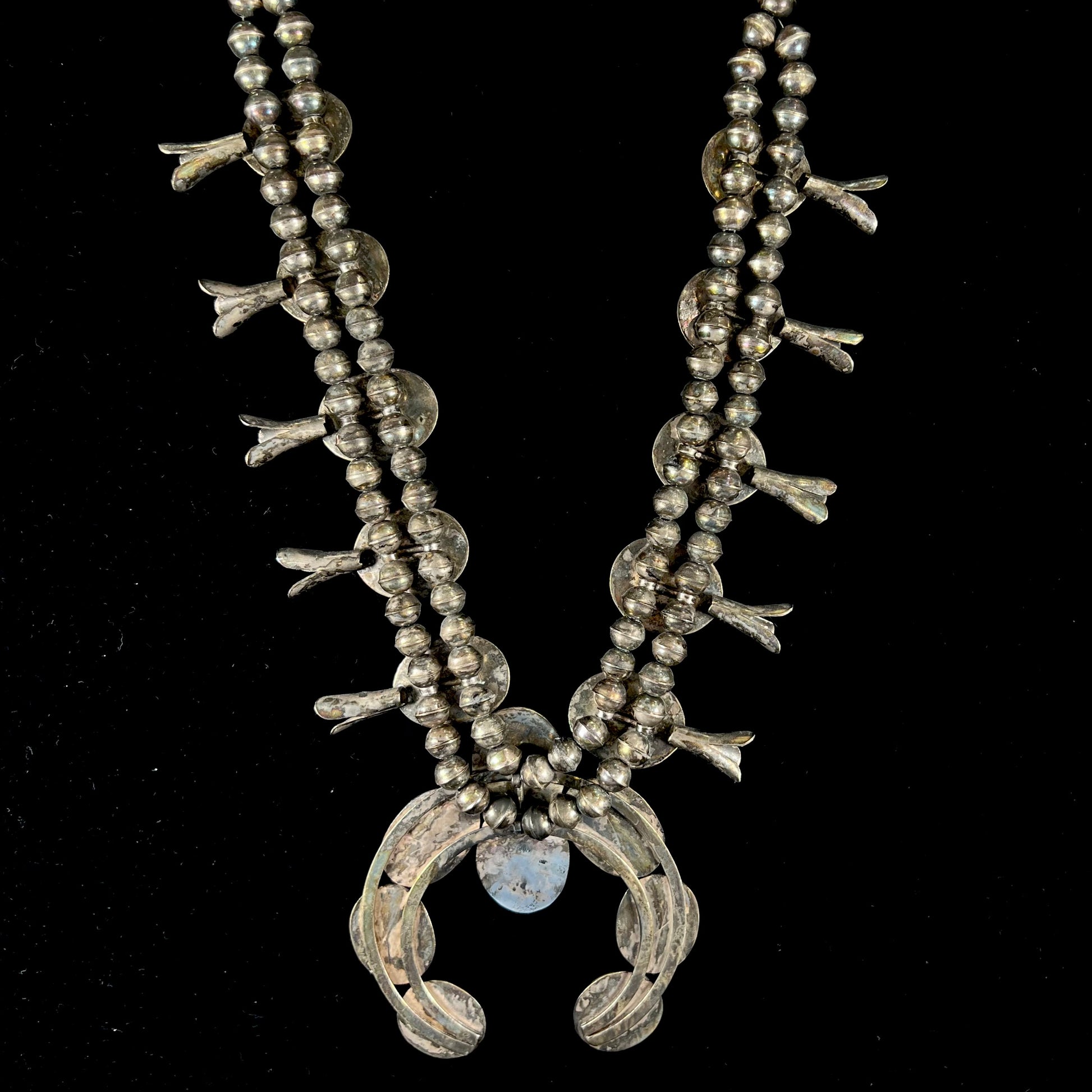 A silver Navajo style unisex squash blossom necklace set with oval cut Sleeping Beauty turquoise stones.