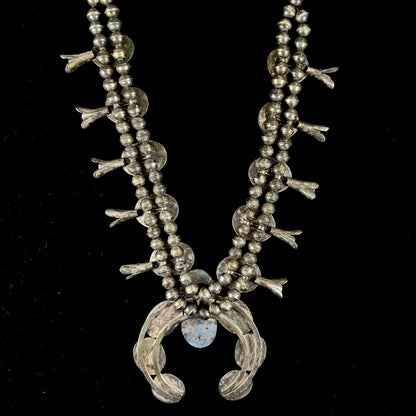 A silver Navajo style unisex squash blossom necklace set with oval cut Sleeping Beauty turquoise stones.