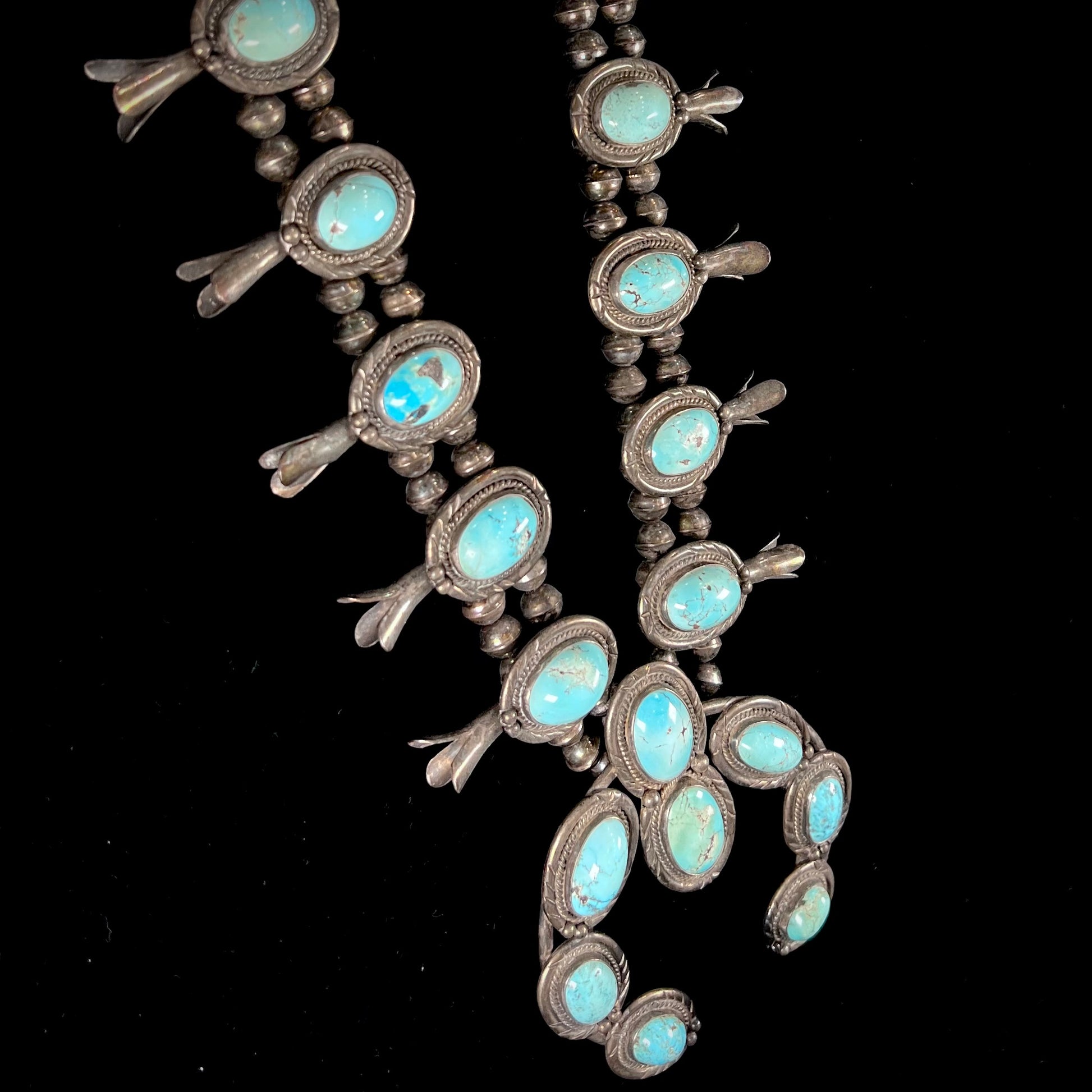 A silver Navajo style unisex squash blossom necklace set with oval cut Sleeping Beauty turquoise stones.