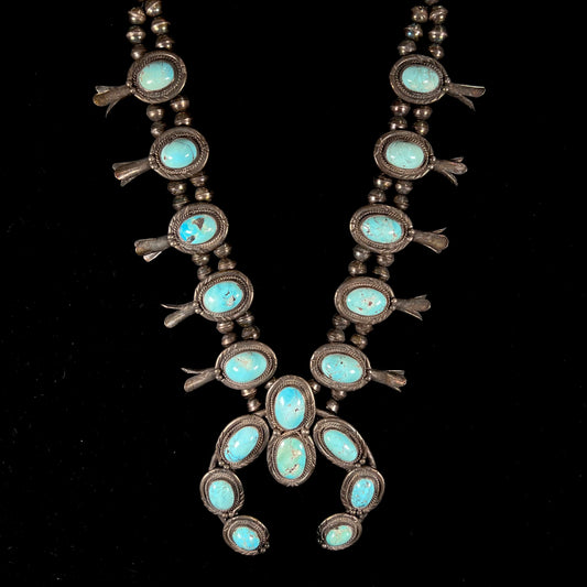 A silver Navajo style unisex squash blossom necklace set with oval cut Sleeping Beauty turquoise stones.