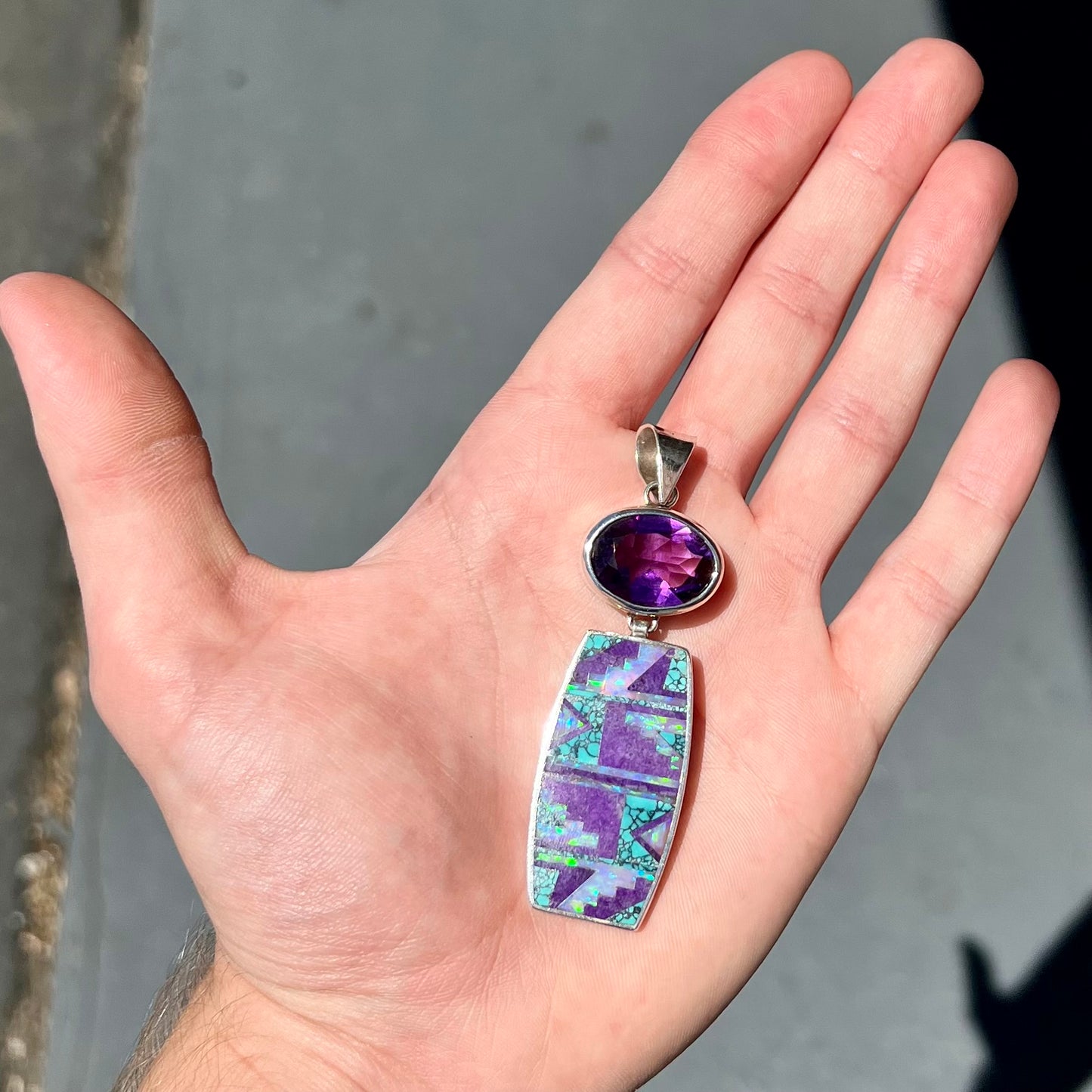 A sterling silver stone inlay necklace set with amethyst, sugilite, spiderweb turquoise, and lab created opal by Navajo artist, Peterson Chee.