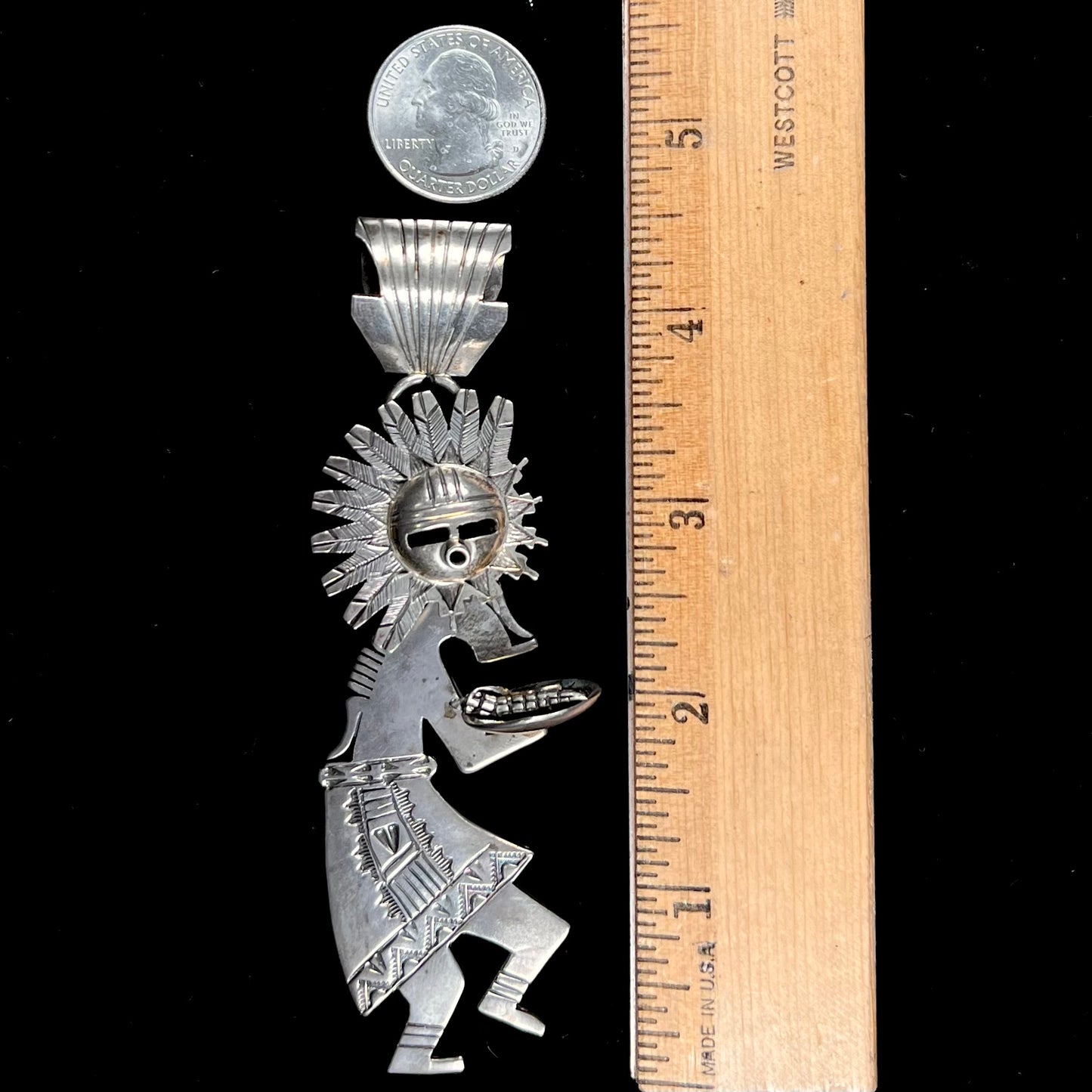 A "Navajo Sunface" kachina doll pendant made from sterling silver by artist Bennie Ration.  The piece measures four and a half inches long.