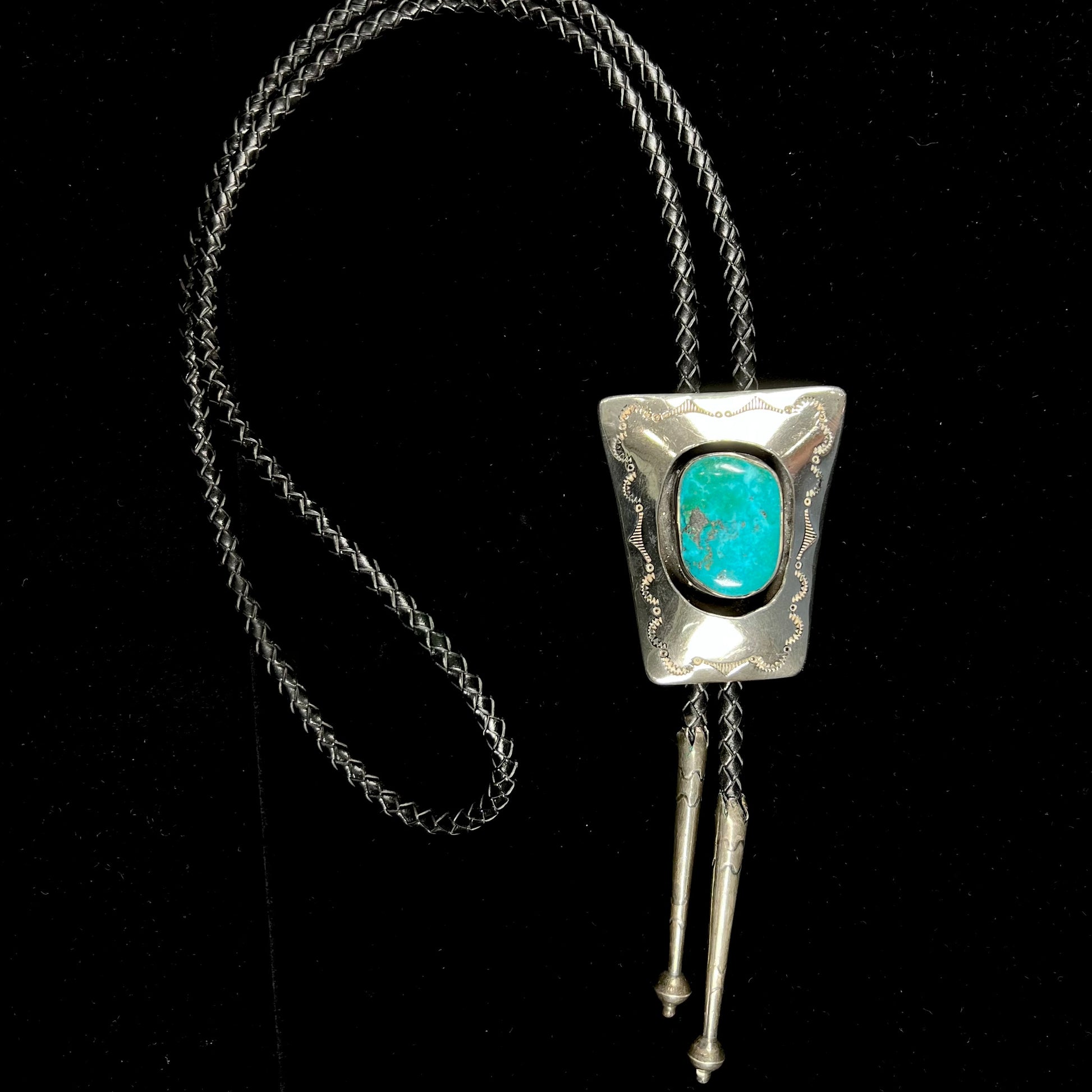 A vintage sterling silver Navajo bolo tie set with Morenci turquoise, handmade by artist Delvin Nelson.