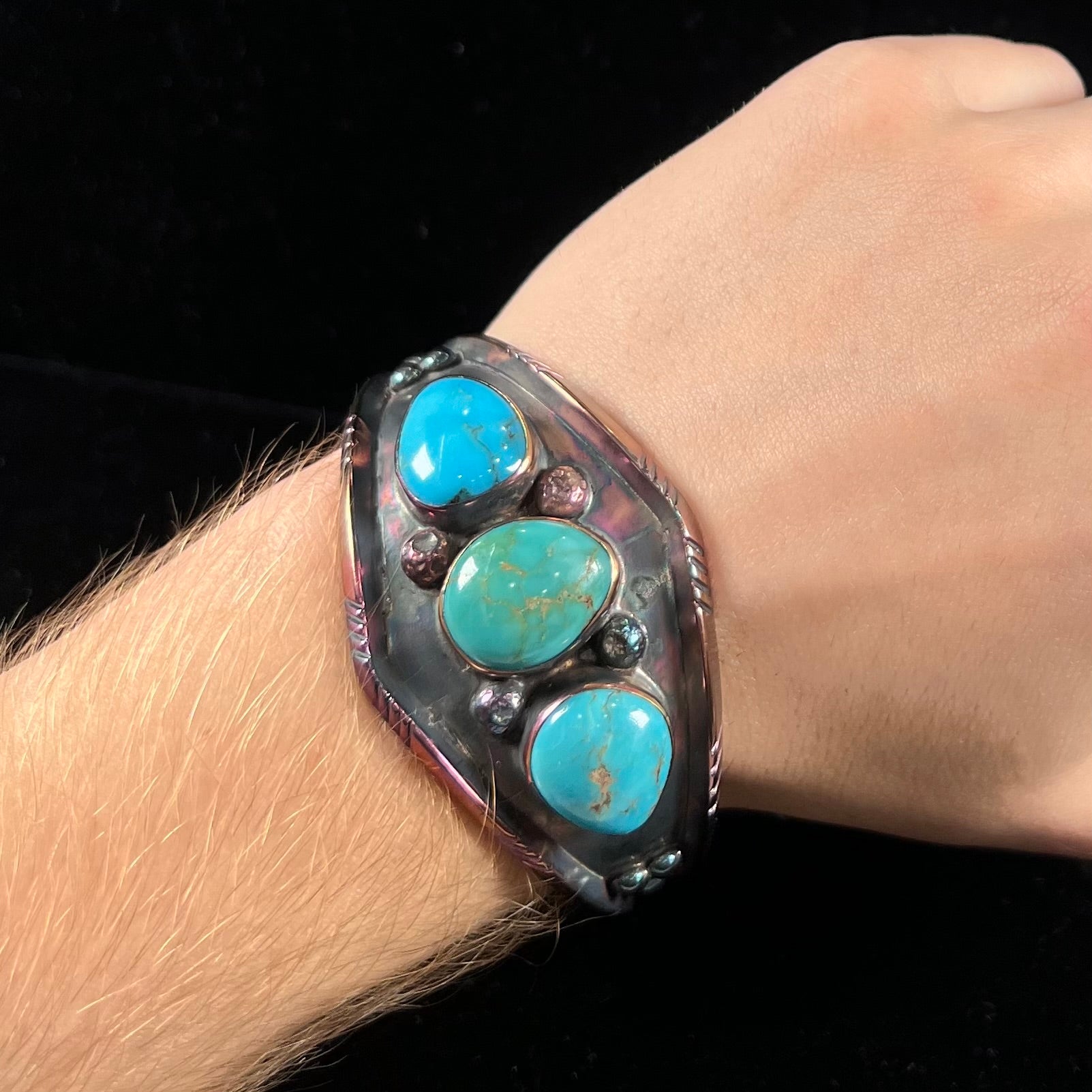 A men's Navajo three stone turquoise cuff bracelet handmade by artist, Dean Brown.  The silver has an iridescent purple patina.