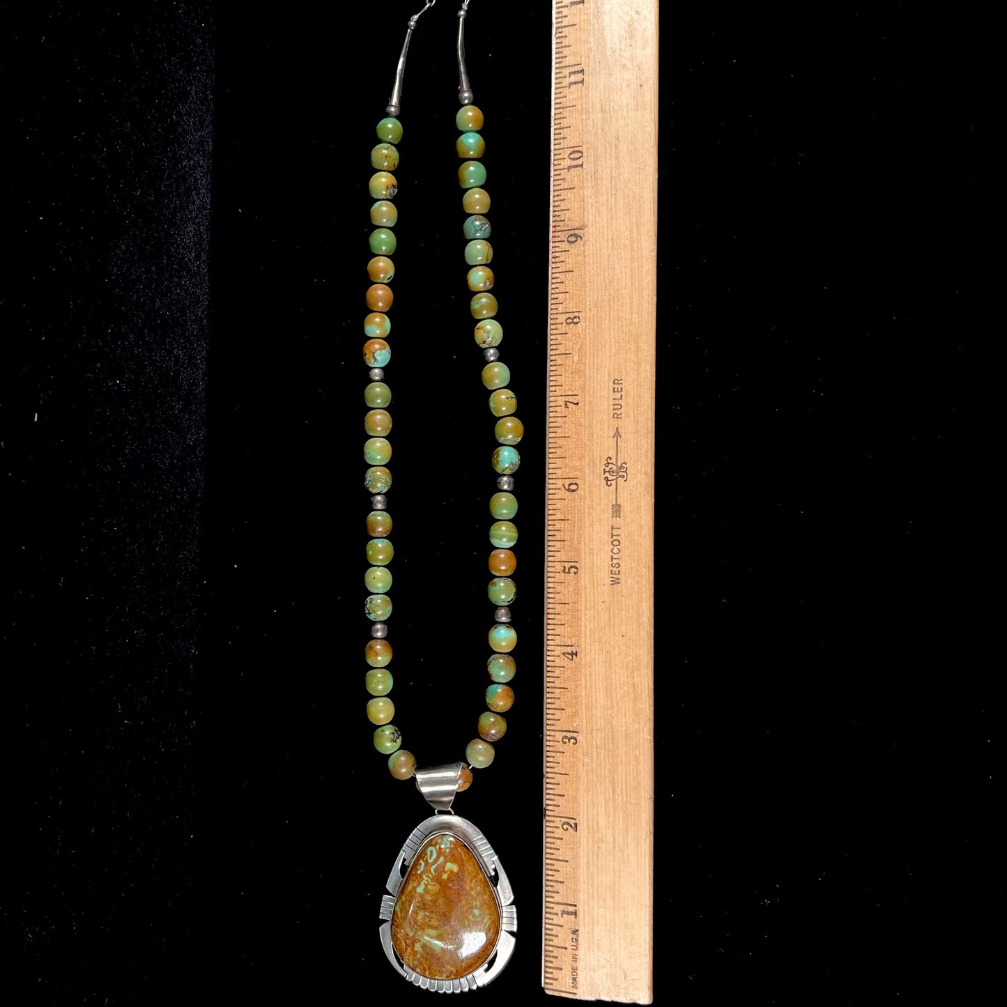 A handmade, likely Navajo silver pendant set with Kingman turquoise on a green Kingman turquoise beaded necklace.