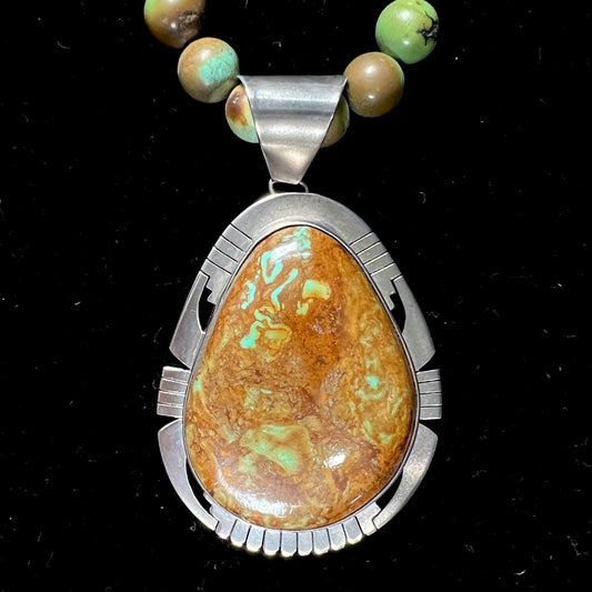 A handmade, likely Navajo silver pendant set with Kingman turquoise on a green Kingman turquoise beaded necklace.