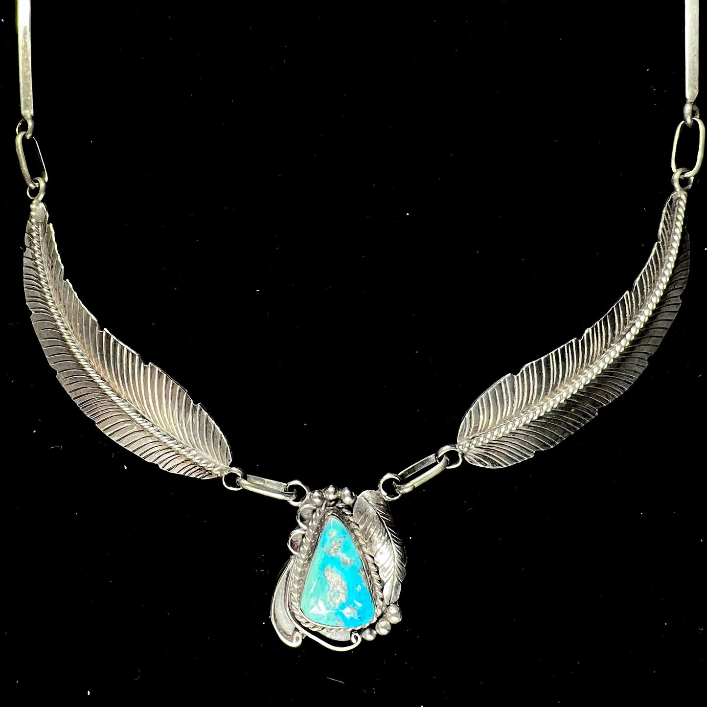 A sterling silver feather motif necklace set with a Sleeping Beauty turquoise stone, handmade by Navajo artist, Jameson Lee.