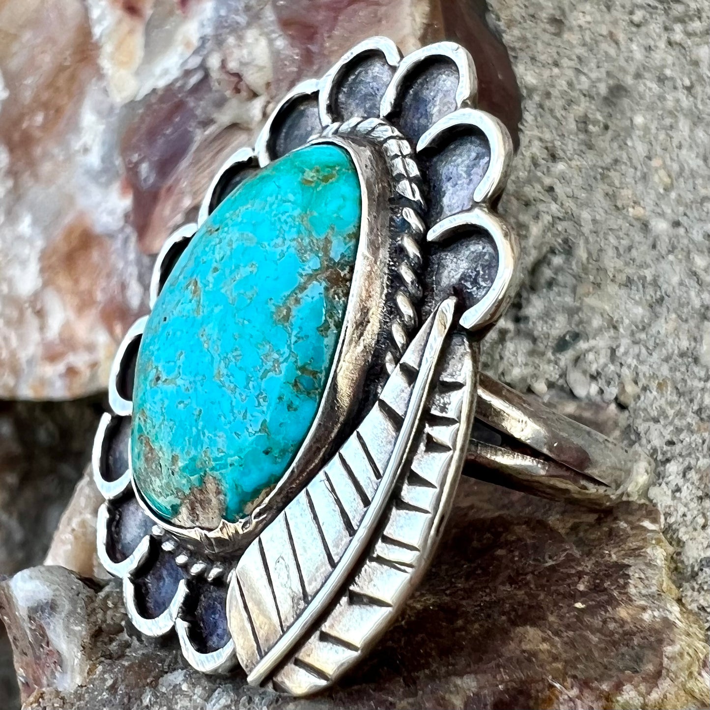 A sterling silver Navajo style ring.  The ring is set with a turquoise stone from Pilot Mountain.  There is a feather decoration next to the stone.