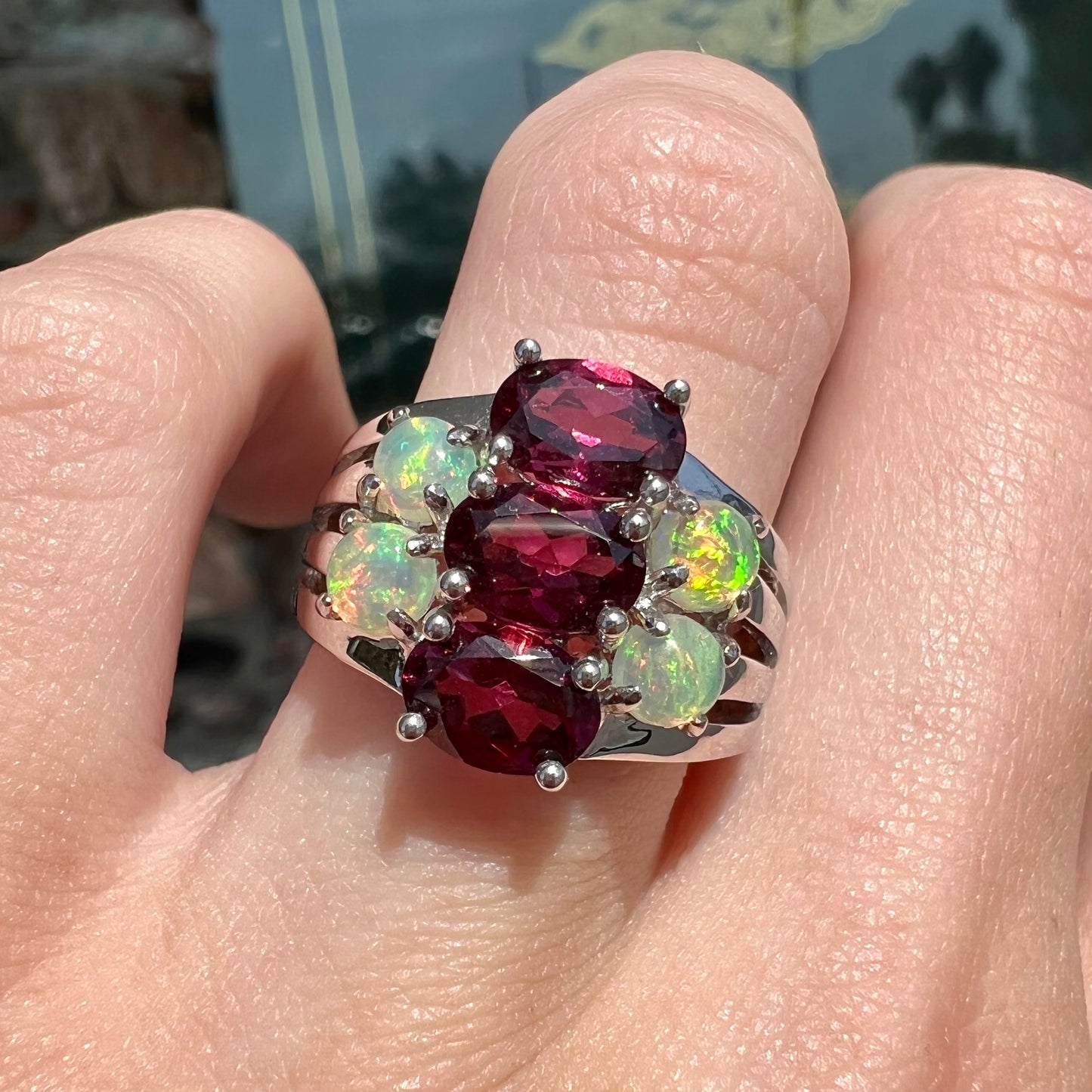 A sterling silver ring set with three oval cut rhodolite garnets and four round cabochon cut Ethiopian opals.
