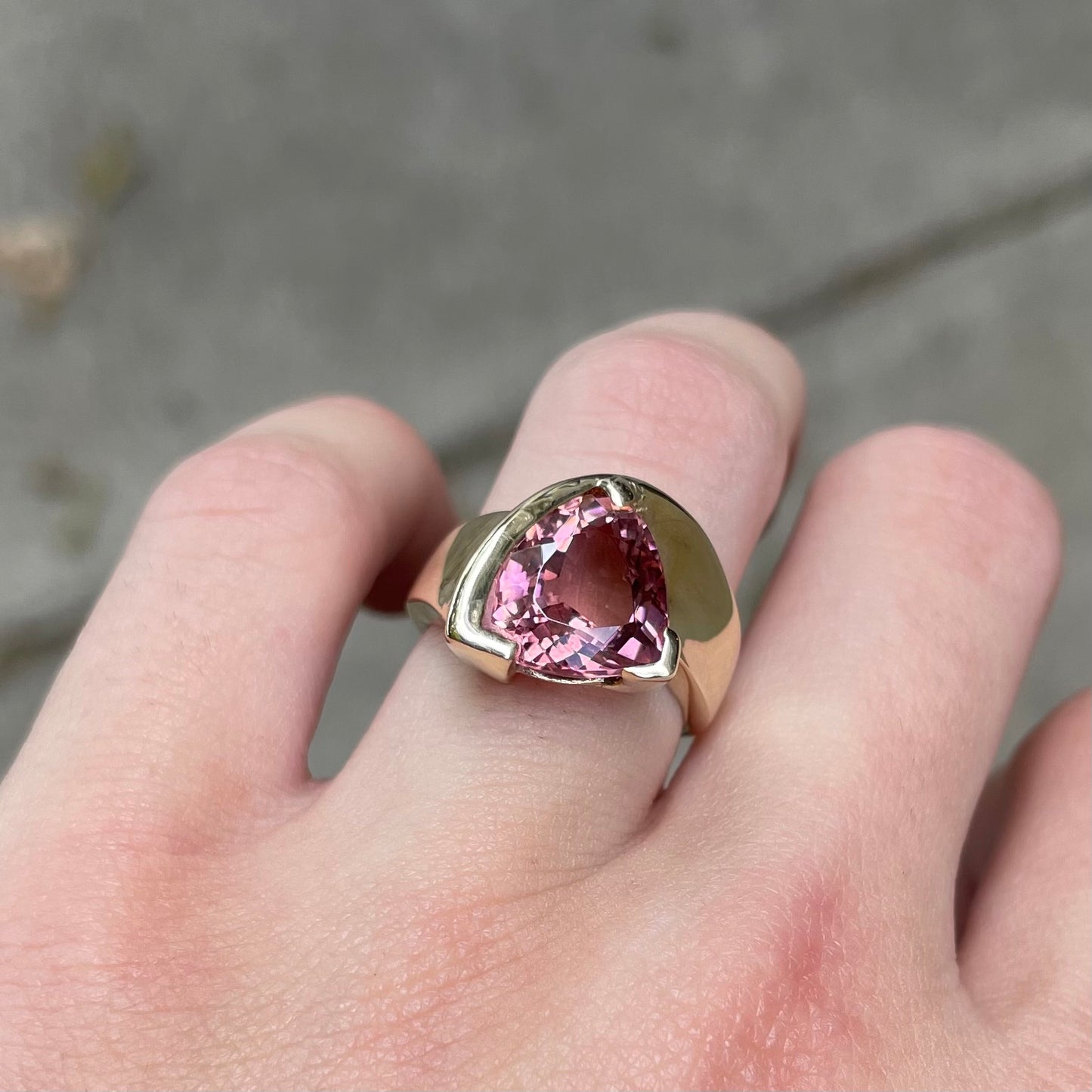 A unisex trillion cut pink tourmaline ring half bezel set in 14k yellow gold.