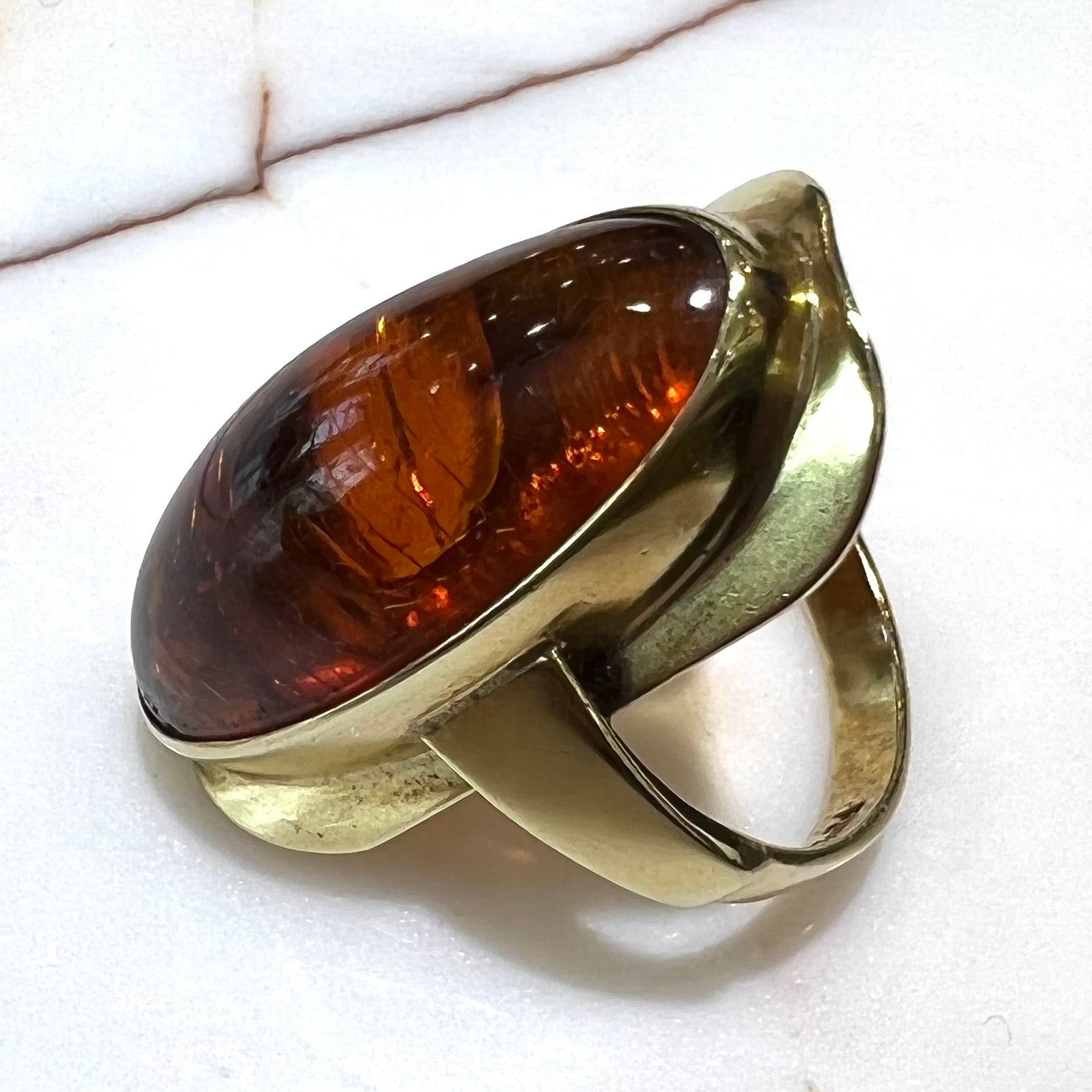 An oval cabochon cut Baltic amber stone set in a yellow gold ring and stamped "AMBER GUILD."