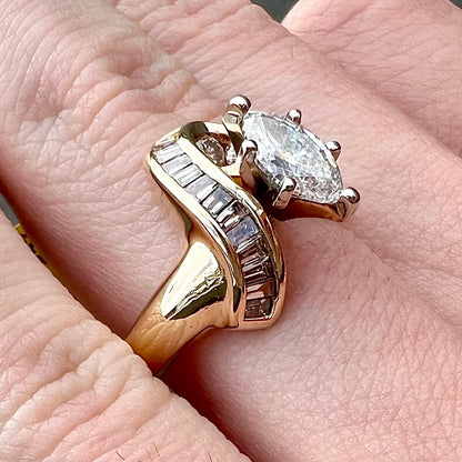 A ladies' marquise cut diamond engagement ring set with round and tapered baguette cut diamond accents.