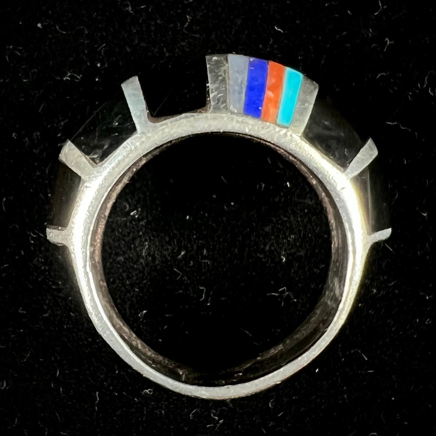 A sterling silver ring inlaid with onyx, turquoise, coral, lapis lazuli, and mother of pearl stones.