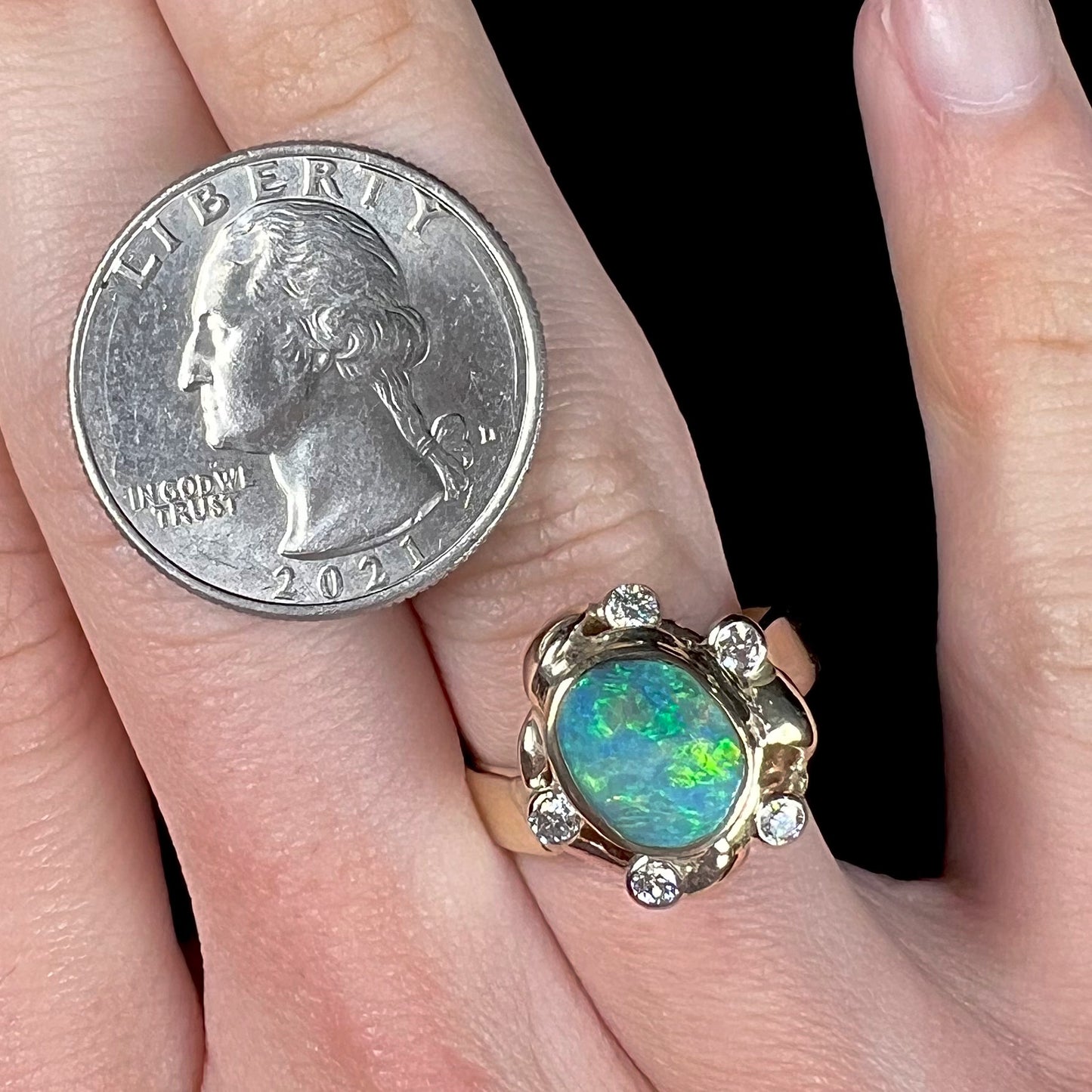 A ladies' yellow gold oval cut natural black opal ring set with five round accent diamonds.