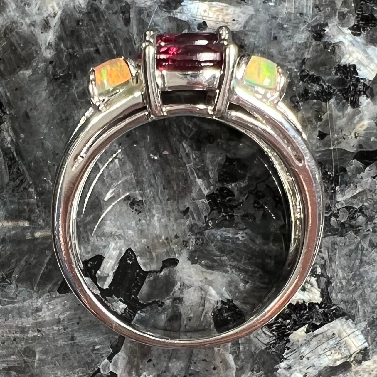 A sterling silver ring set with three oval cut rhodolite garnets and four round cabochon cut Ethiopian opals.