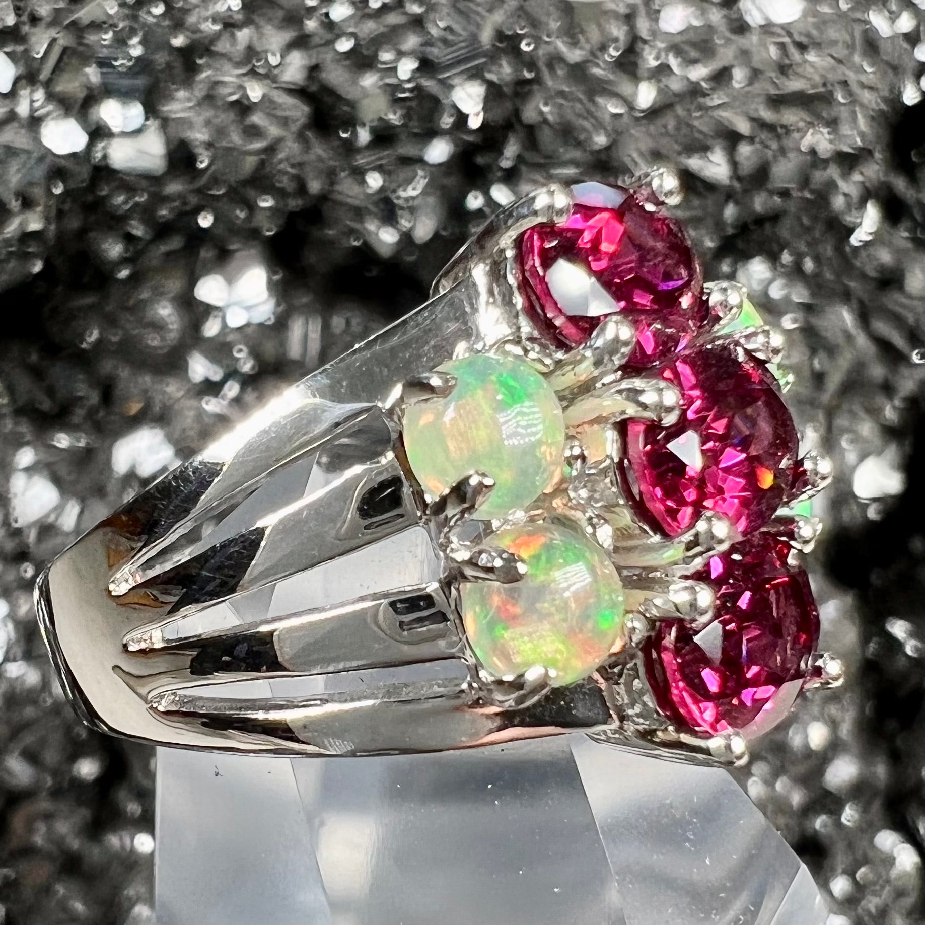A sterling silver ring set with three oval cut rhodolite garnets and four round cabochon cut Ethiopian opals.