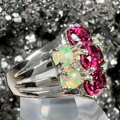 A sterling silver ring set with three oval cut rhodolite garnets and four round cabochon cut Ethiopian opals.