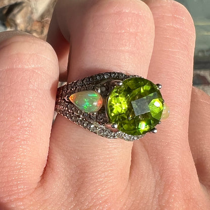 A sterling silver ring set with one large round peridot stone set between two pear shape cabochon Ethiopian opals.  Cubic zirconia stones line the ring.