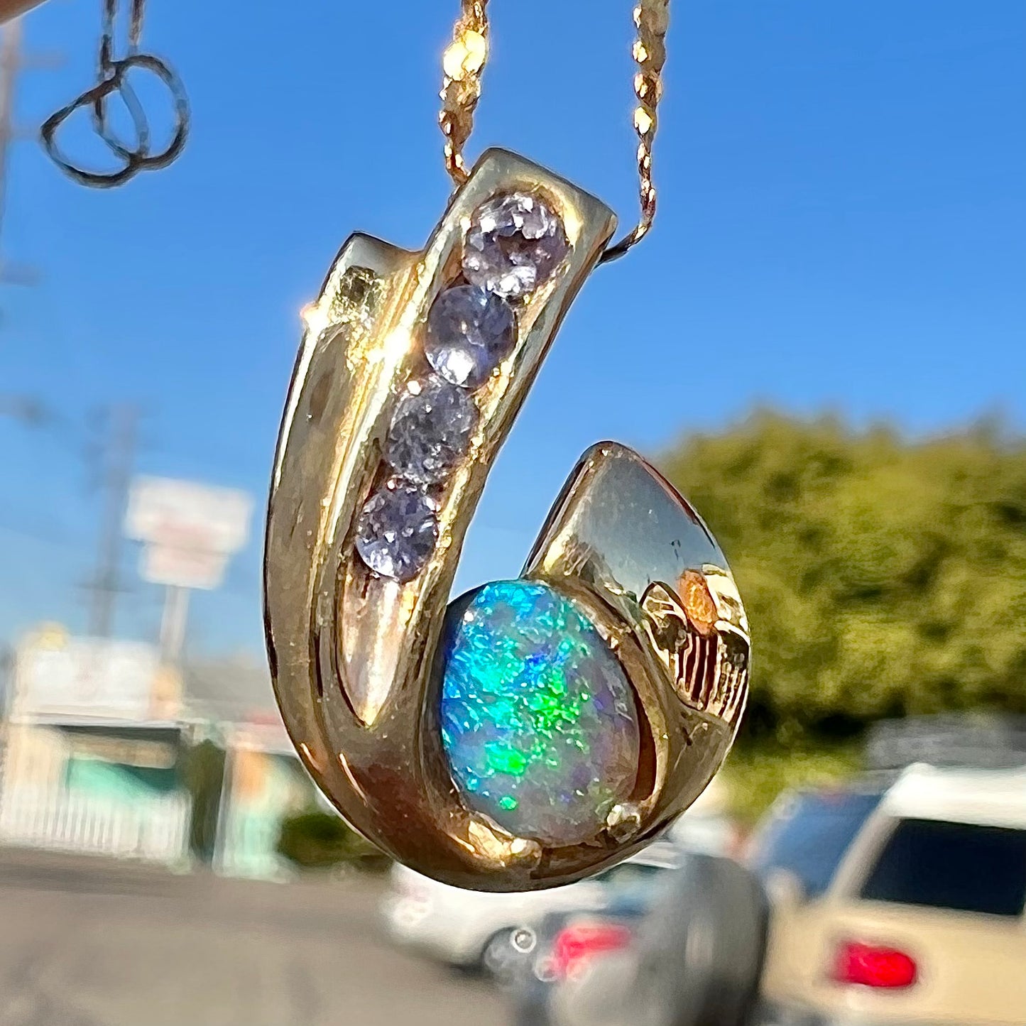 A Lightning Ridge black crystal opal necklace set with blue tanzanite in yellow gold.  Gold chain not included.