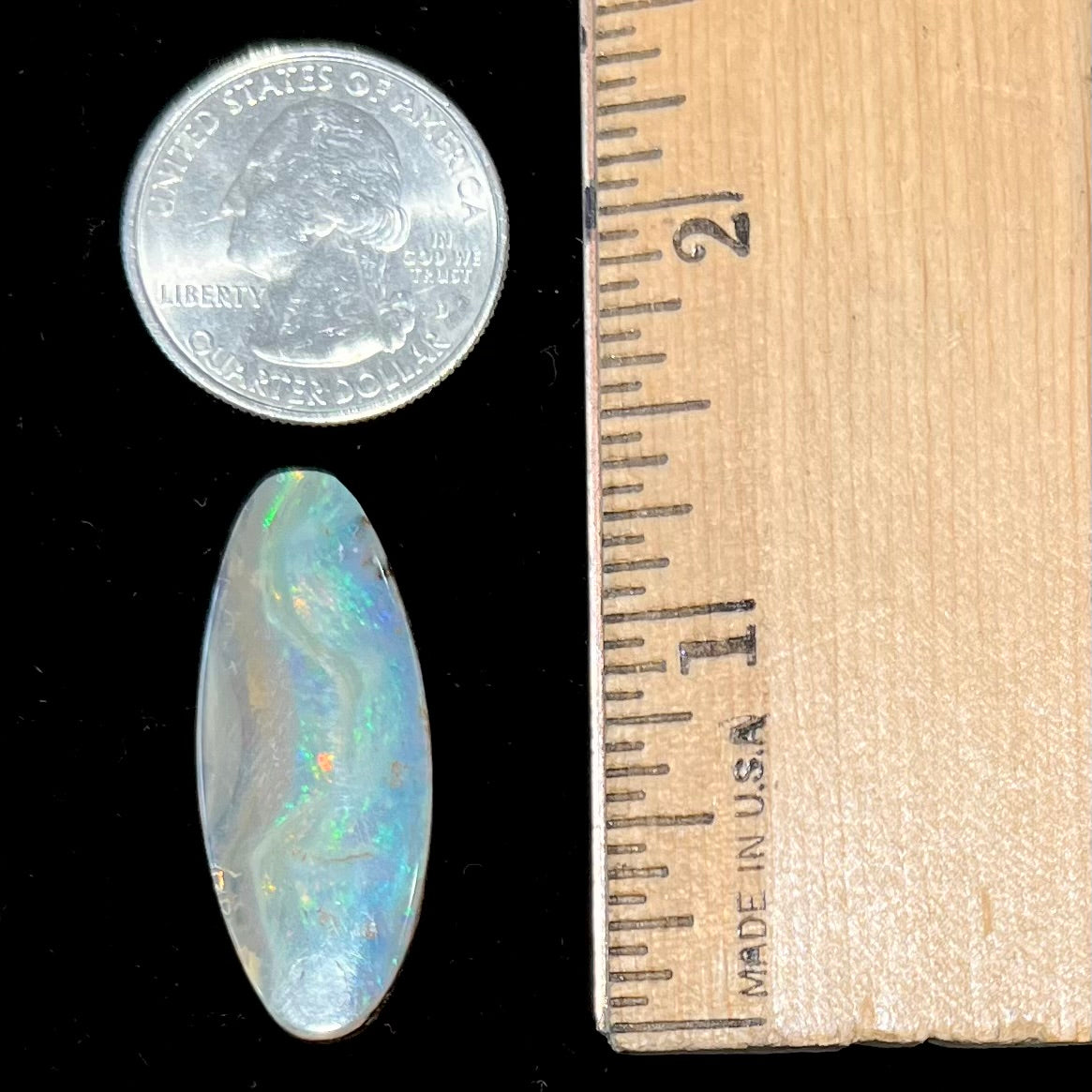 A loose, oval cabochon cut opal from Quilpie, Australia.  Blue, red, and green colors can be seen.