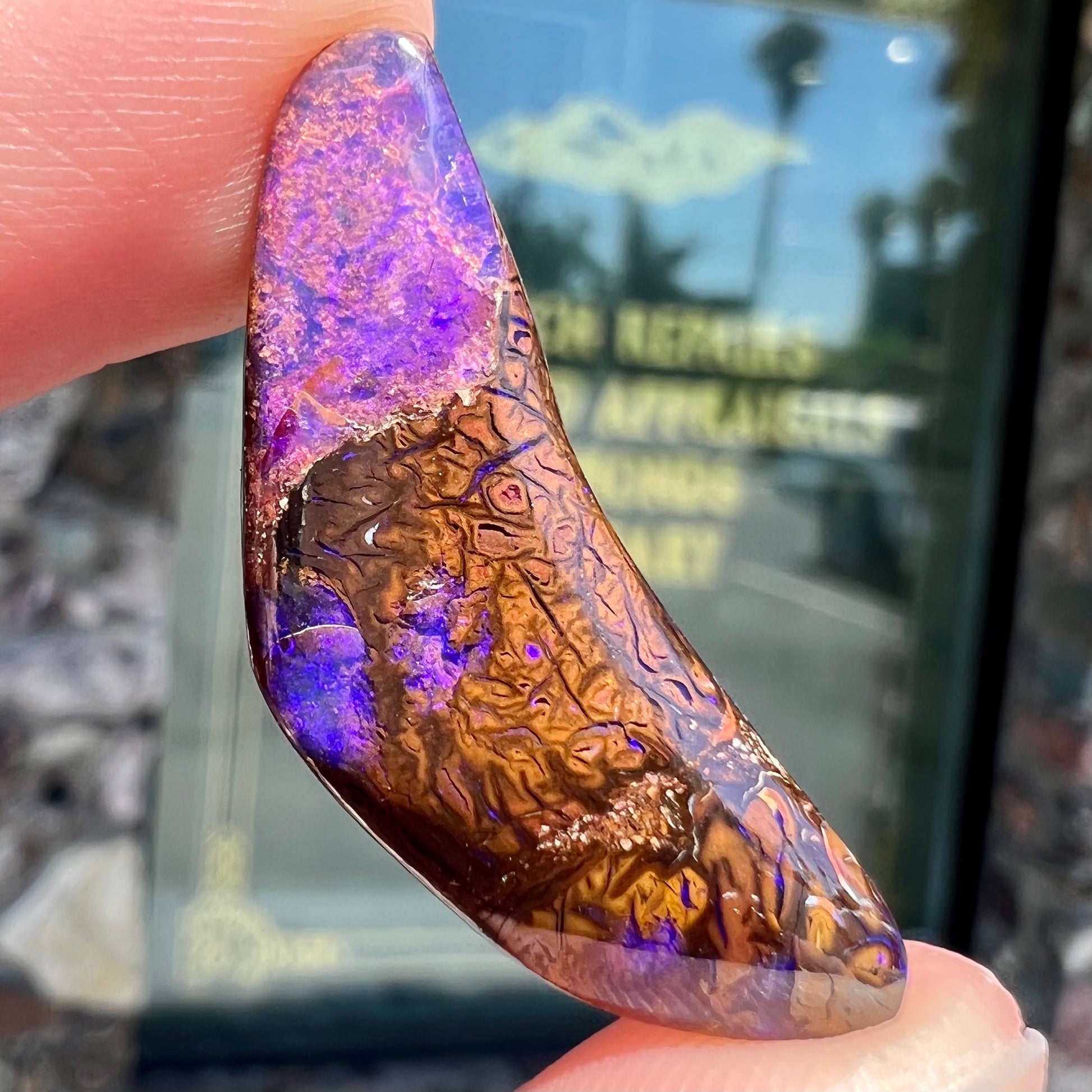 A loose boomerang shaped purple boulder opal stone from Quilpie, Australia.