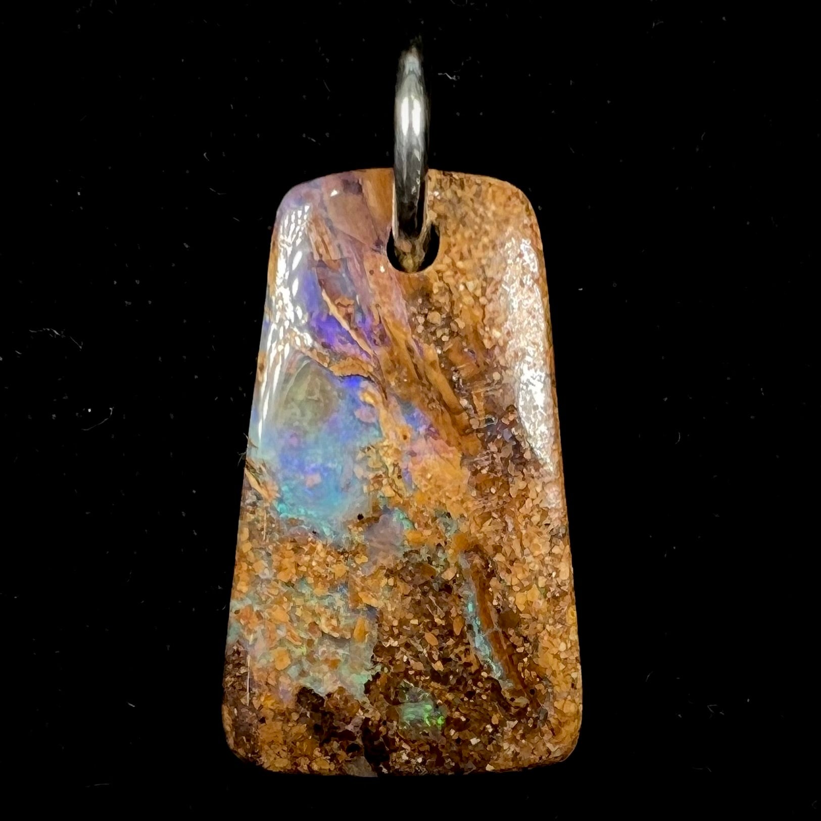 A drilled boulder opal stone with a sterling silver ring through the hole to be worn as a pendant.