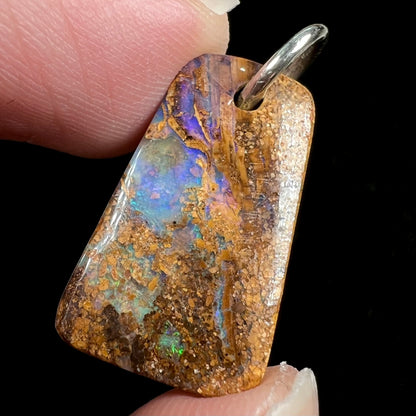 A drilled boulder opal stone with a sterling silver ring through the hole to be worn as a pendant.