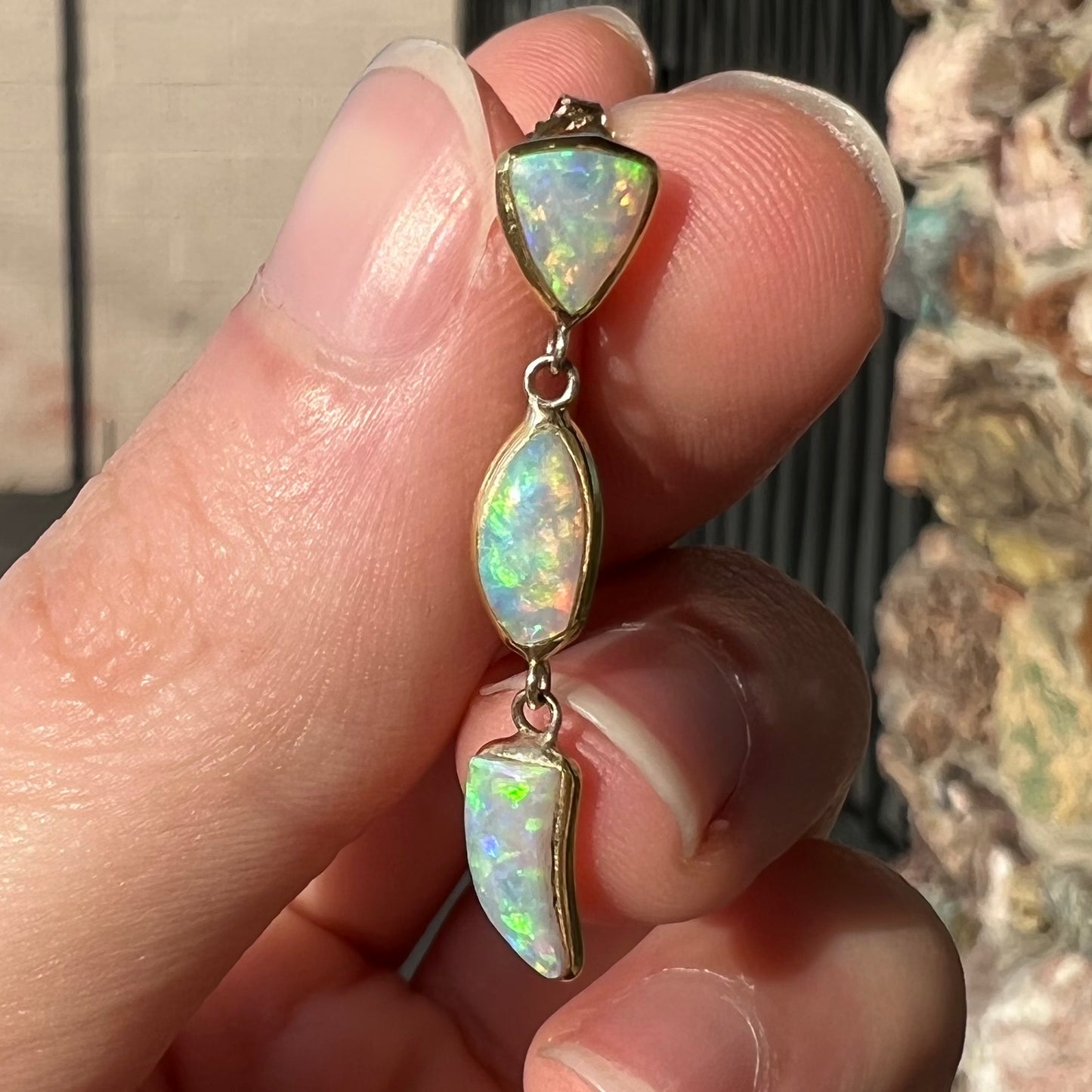 A pair of yellow gold push-back dangle earrings set with three white crystal opals in each.