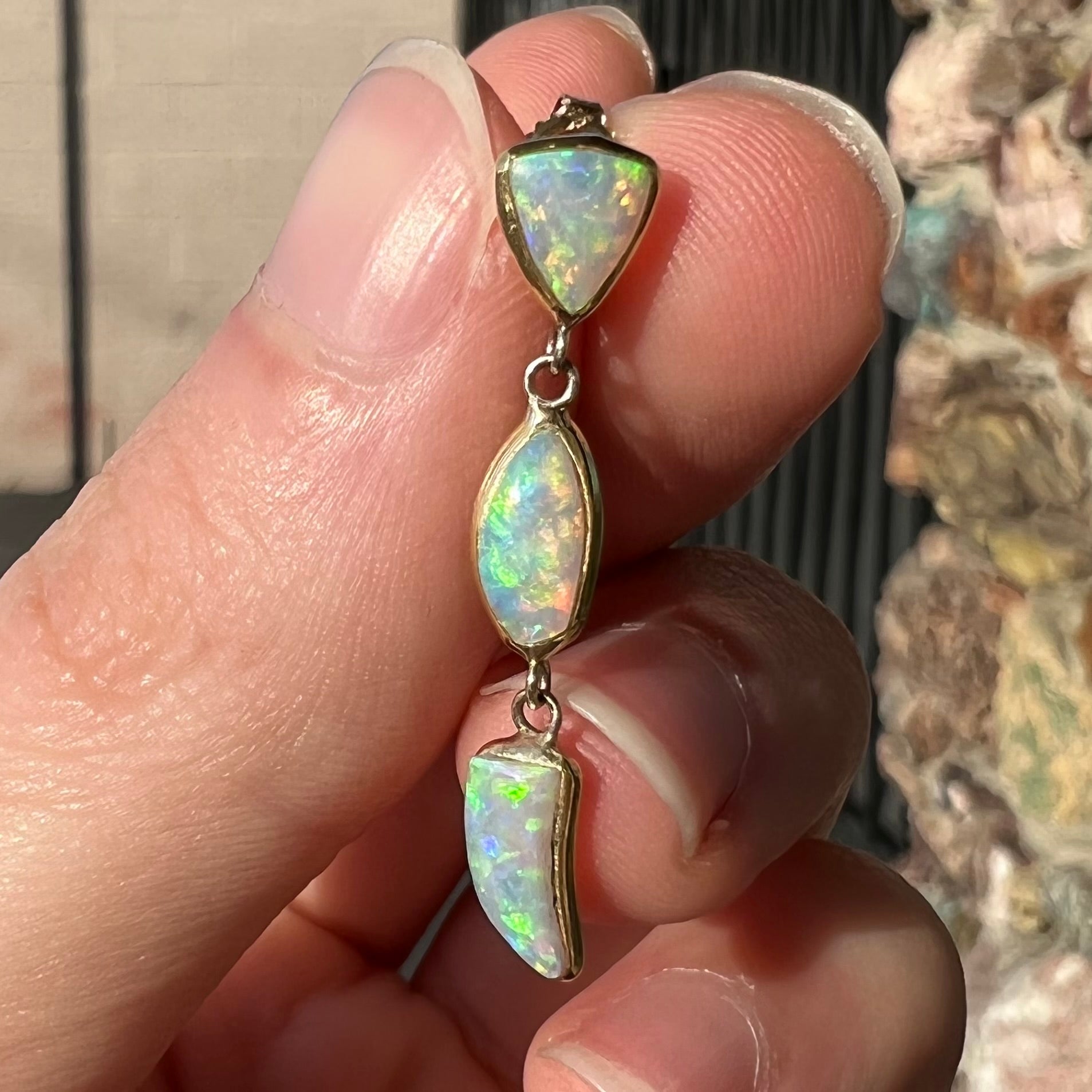 A pair of yellow gold push-back dangle earrings set with three white crystal opals in each.