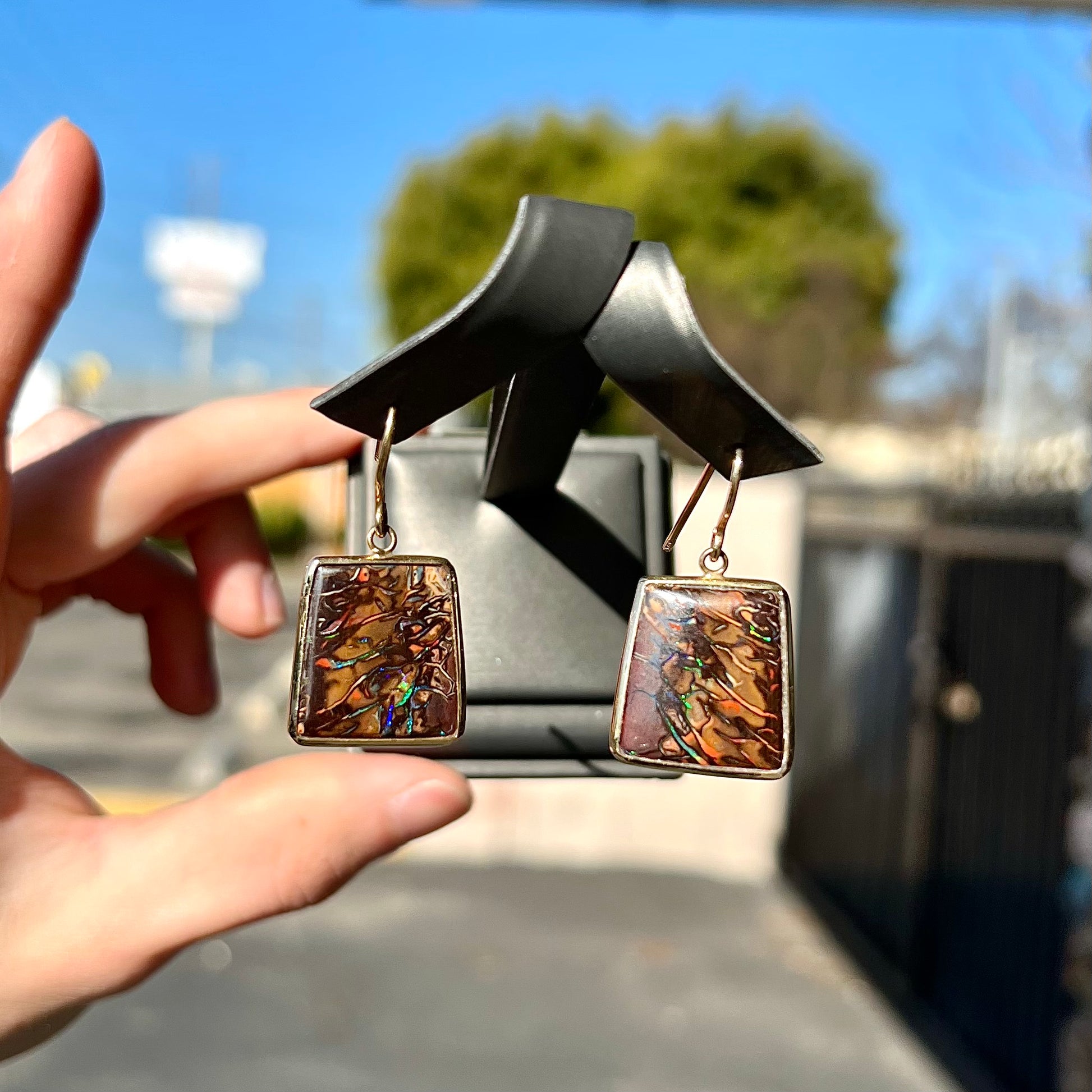 A pair of yellow gold French wire dangle earrings set with Koroit boulder opal.
