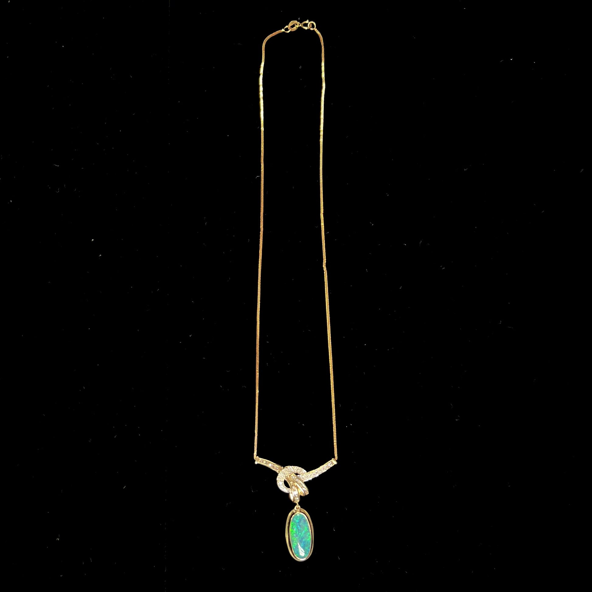 A gold black opal and diamond necklace.  There are round, princess cut, and baguette cut diamonds.