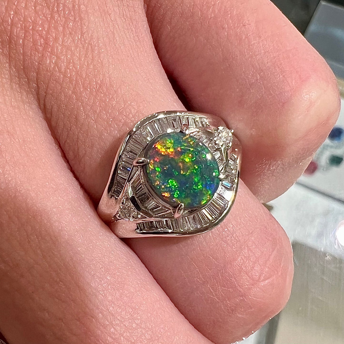 A platinum Lightning Ridge black opal ring set with baguette cut diamonds.  The opal is an oval cabochon cut.