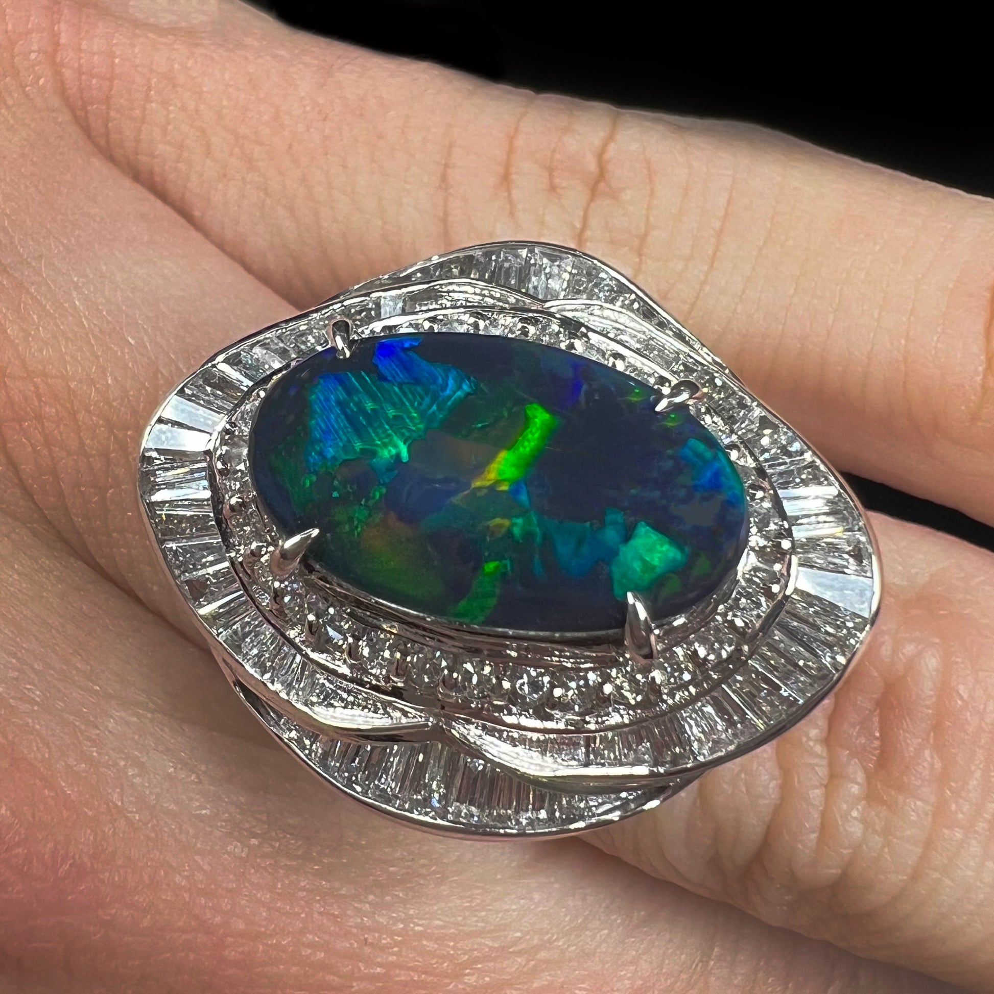 A ladies' platinum diamond halo ring set with a natural black opal stone from Lightning Ridge, Australia.