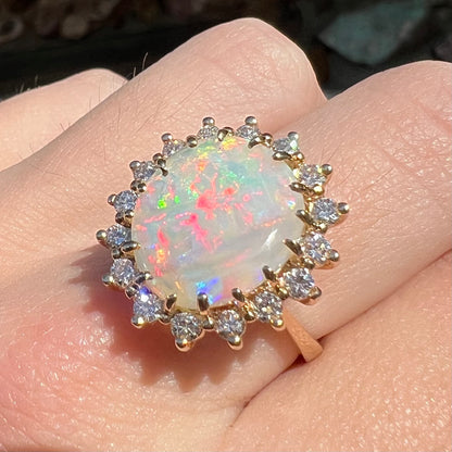 A ladies' diamond halo ring set with a Coober Pedy opalized seashell in yellow gold.