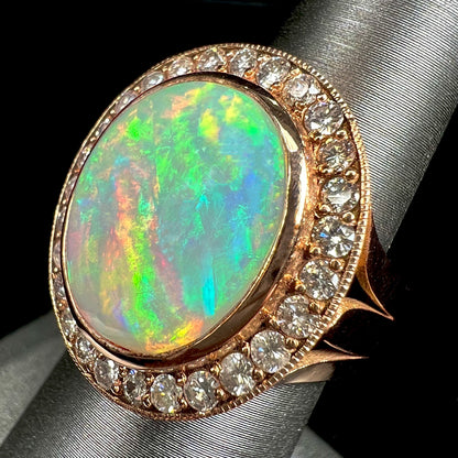 A ladies' natural crystal fire opal ring set in rose gold with a halo of round cut diamonds.