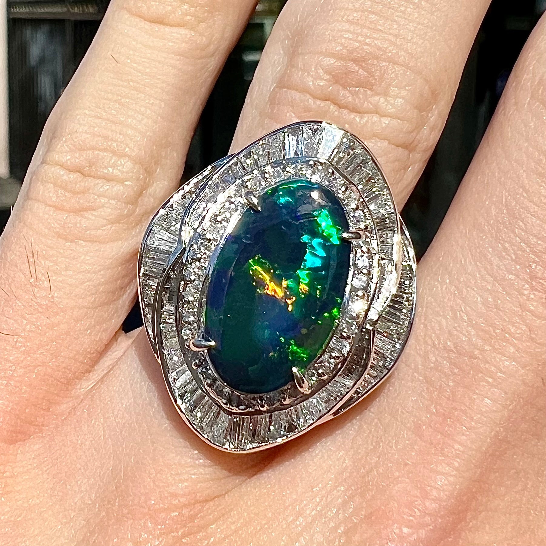 A ladies' platinum diamond halo ring set with a natural black opal stone from Lightning Ridge, Australia.