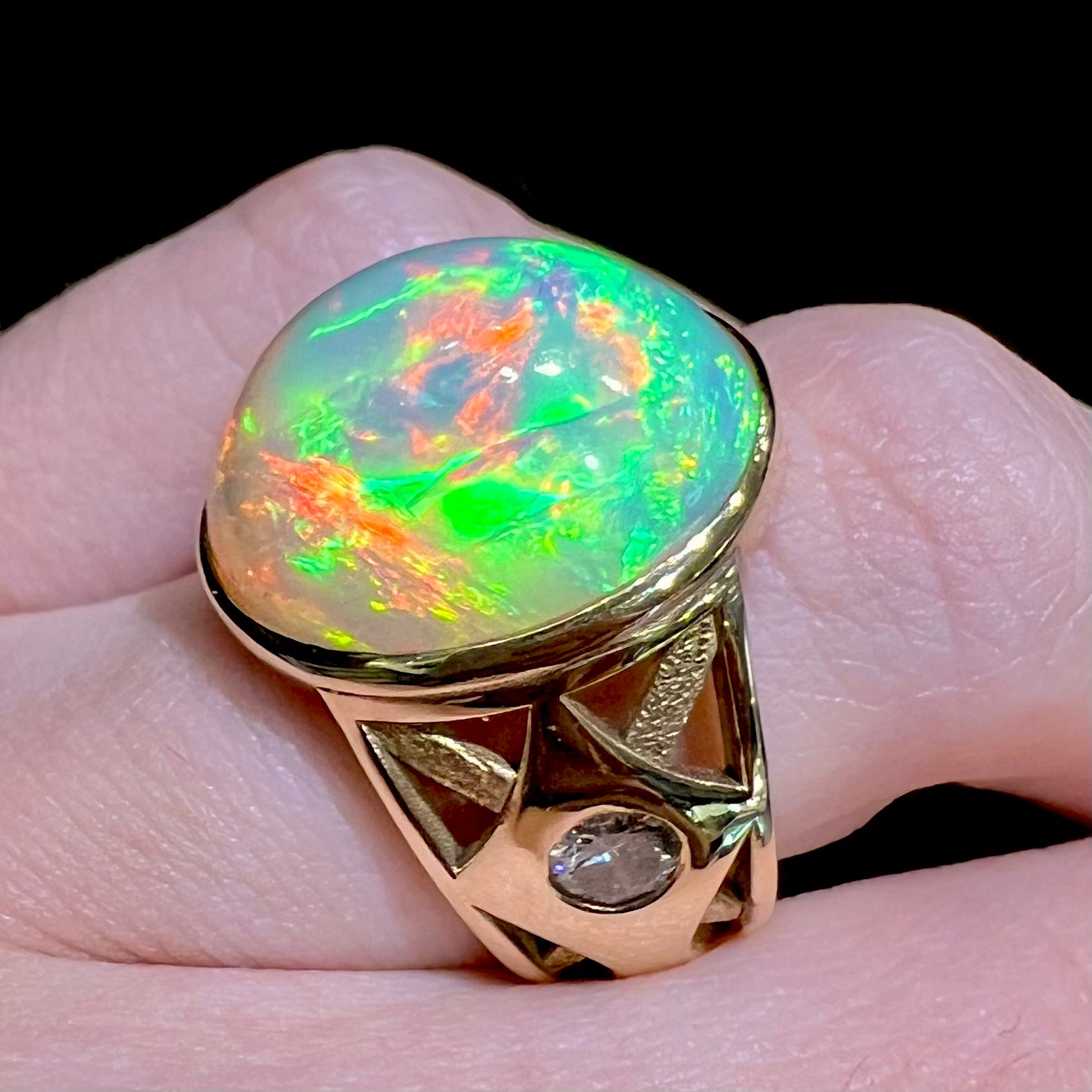 A custom yellow gold men's ring set with two diamonds and a large oval cabochon cut opal from Ethiopia, Africa.