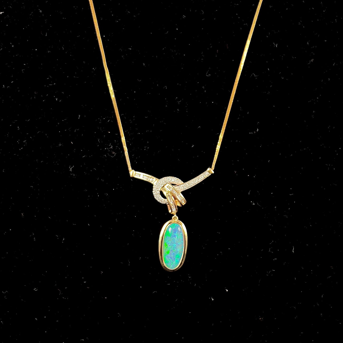 A gold black opal and diamond necklace.  There are round, princess cut, and baguette cut diamonds.