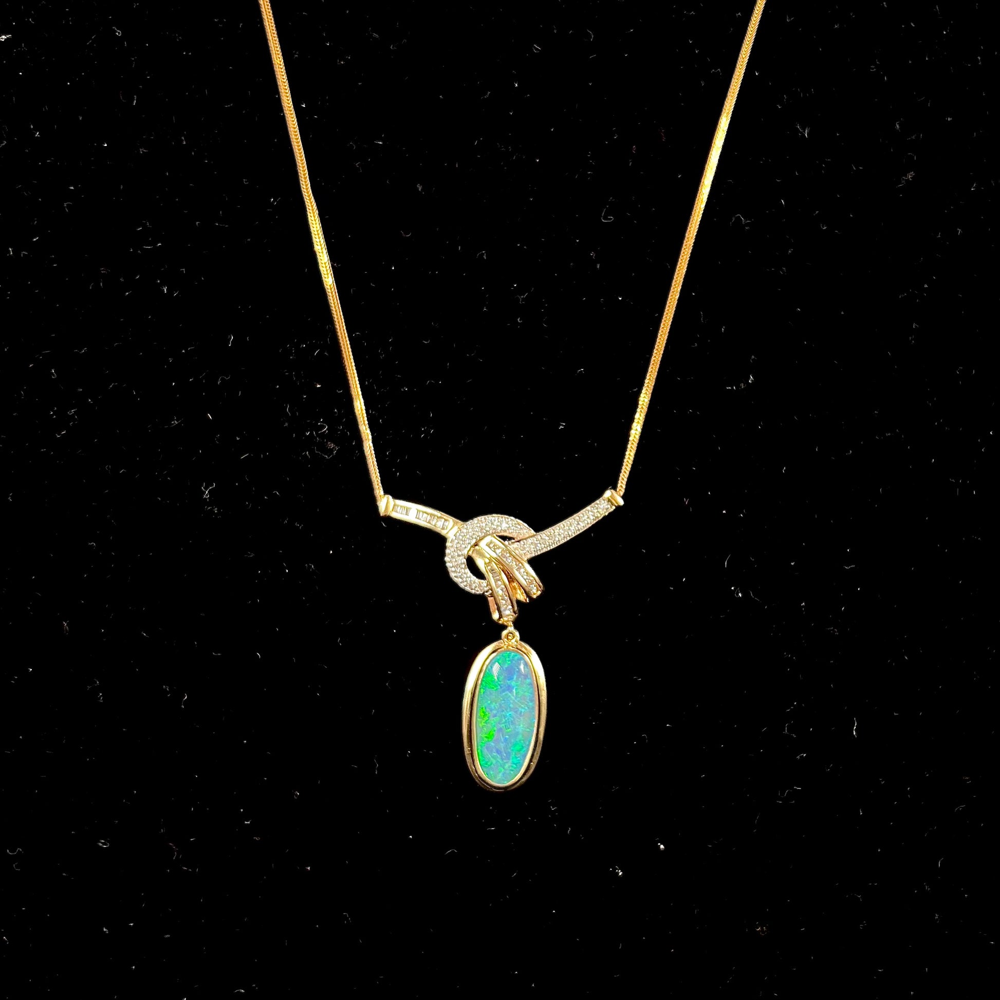 A gold black opal and diamond necklace.  There are round, princess cut, and baguette cut diamonds.