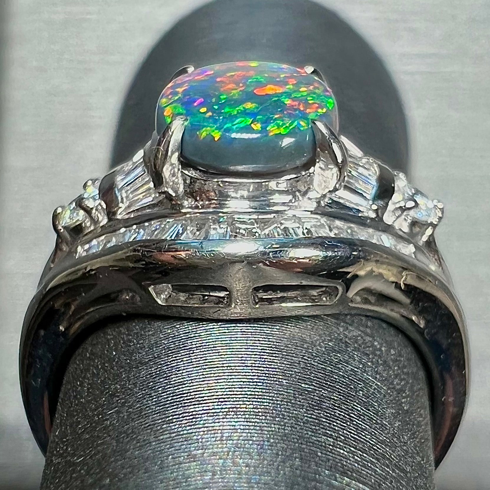 A platinum Lightning Ridge black opal ring set with baguette cut diamonds.  The opal is an oval cabochon cut.