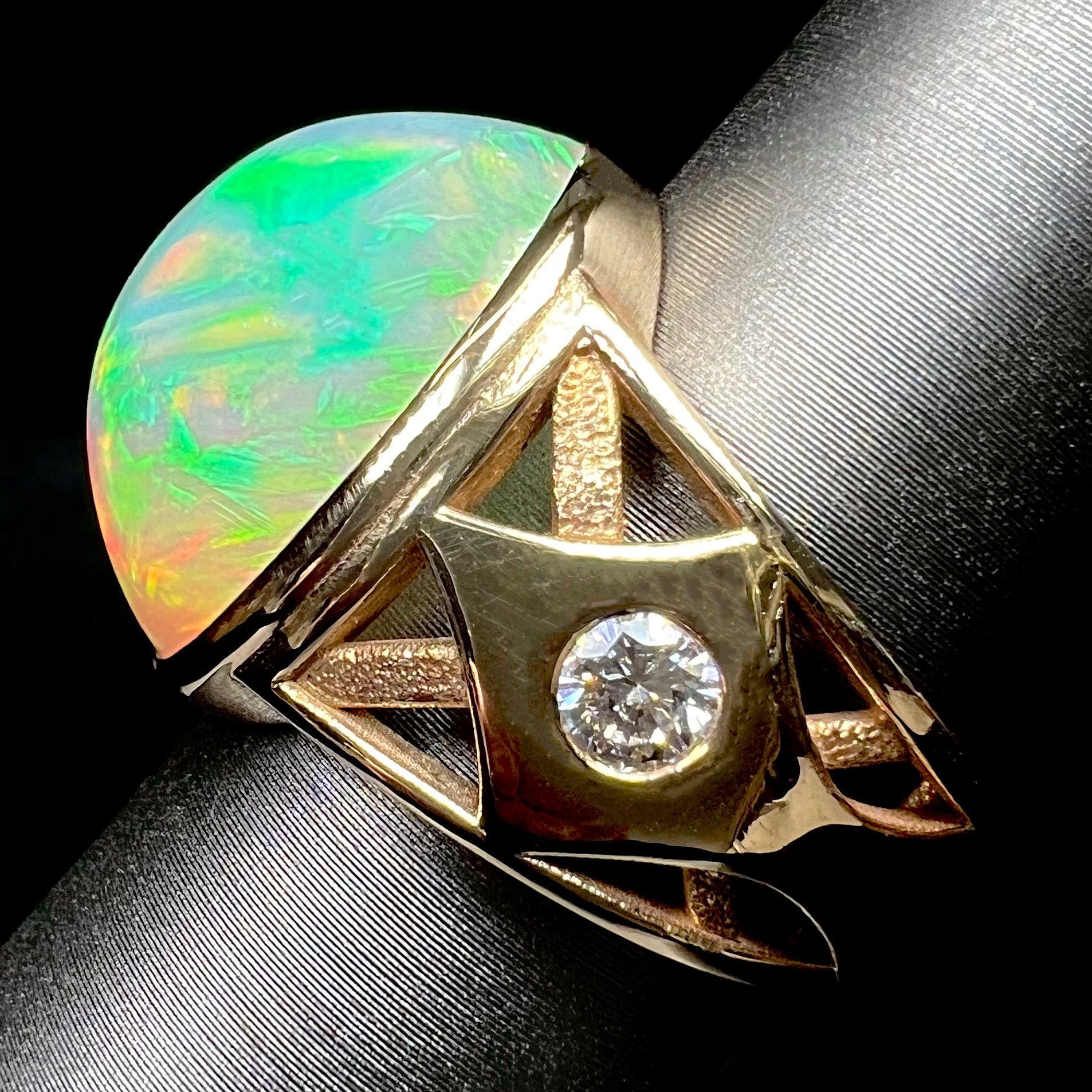 A custom yellow gold men's ring set with two diamonds and a large oval cabochon cut opal from Ethiopia, Africa.