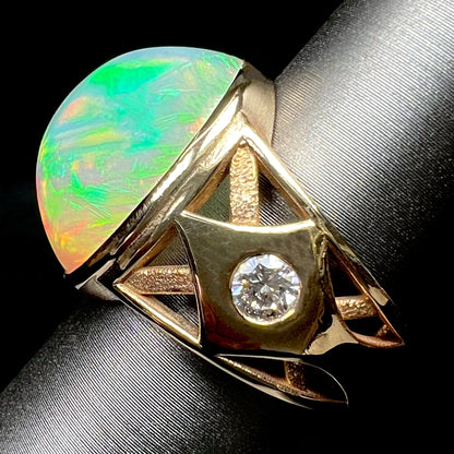 A custom yellow gold men's ring set with two diamonds and a large oval cabochon cut opal from Ethiopia, Africa.