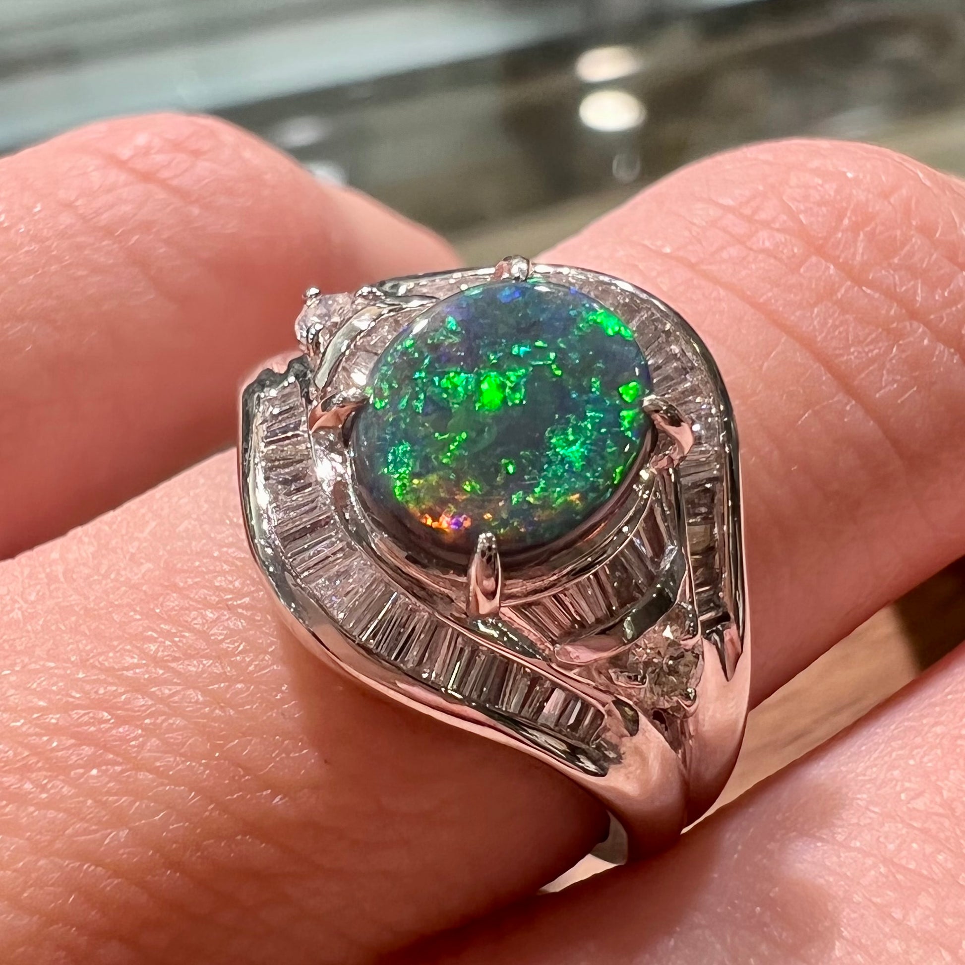 A platinum Lightning Ridge black opal ring set with baguette cut diamonds.  The opal is an oval cabochon cut.