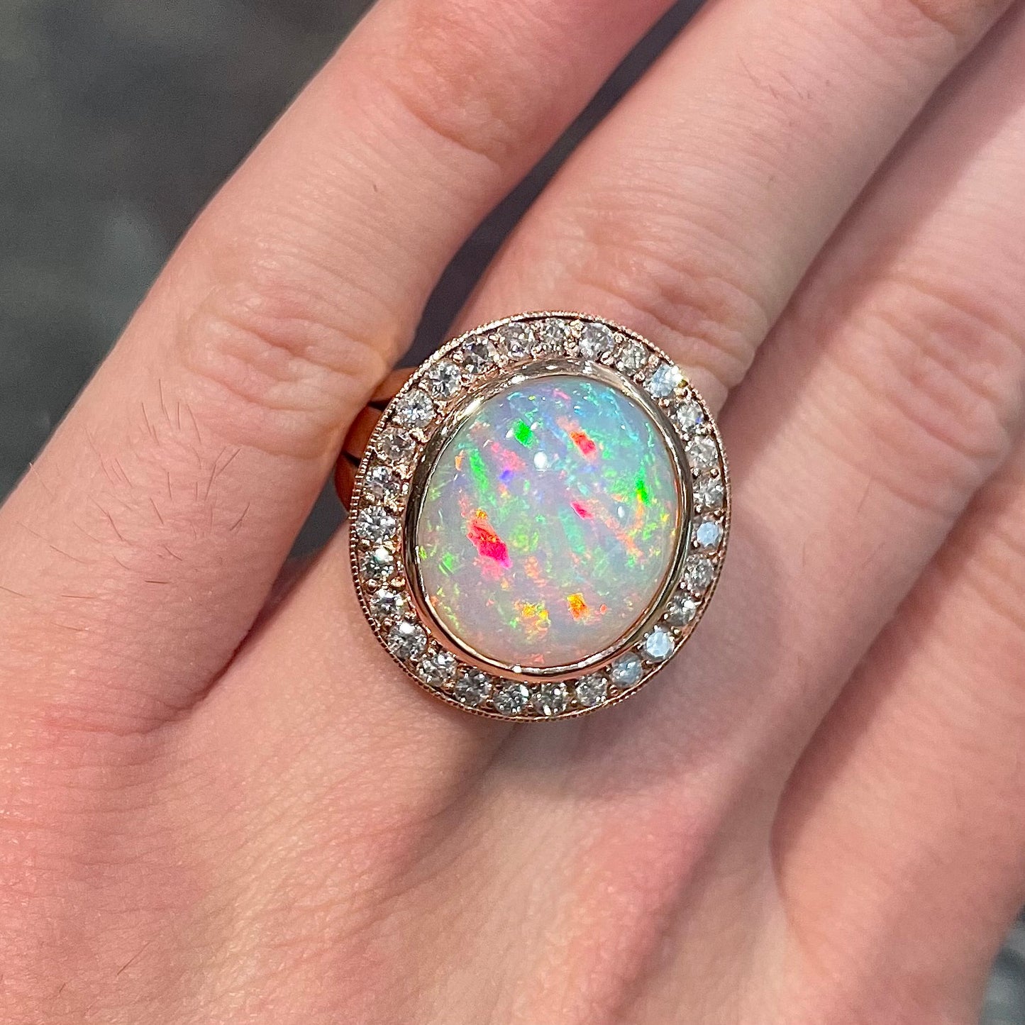 A large, Australian white crystal opal set in a rose gold and diamond halo ring.