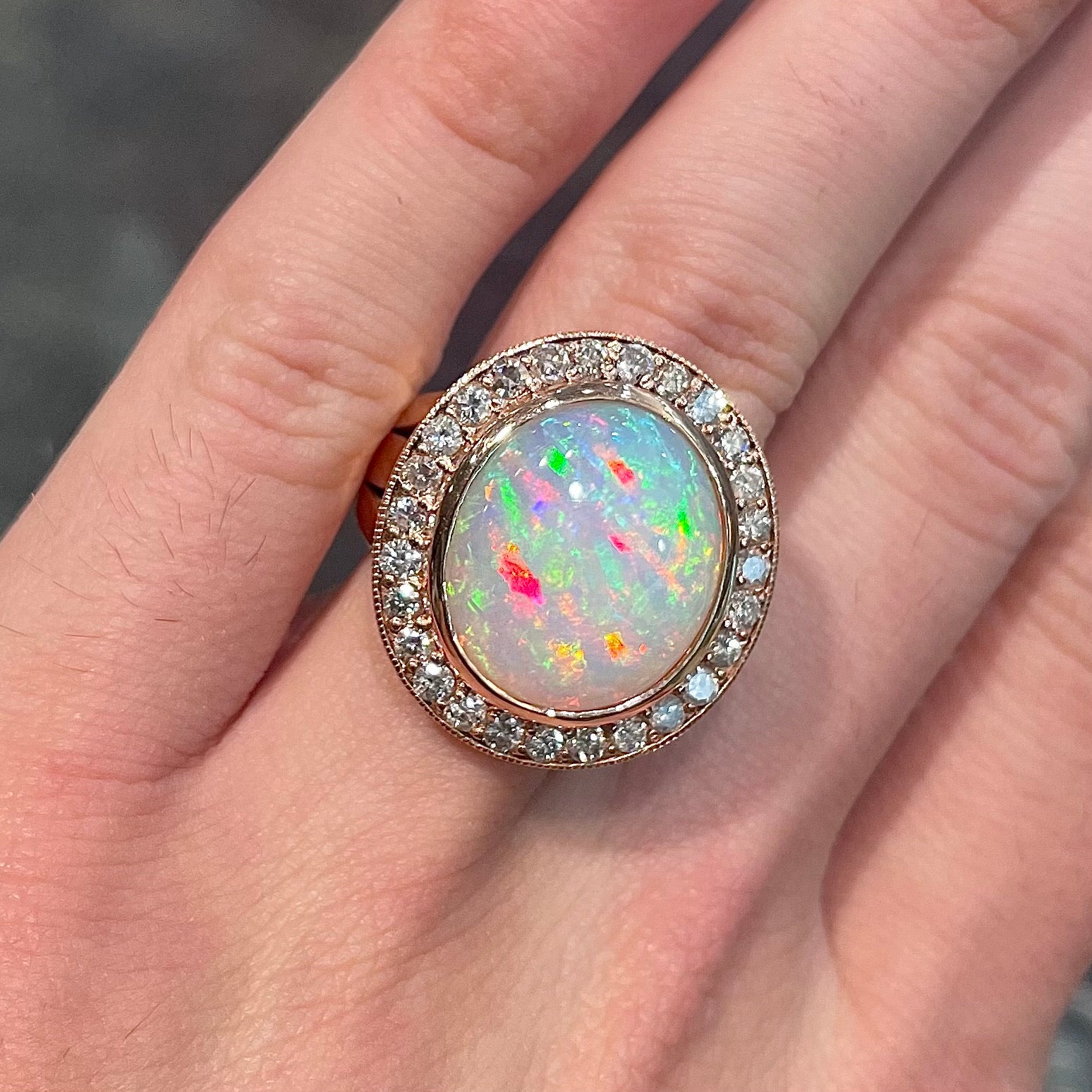 A large, Australian white crystal opal set in a rose gold and diamond halo ring.