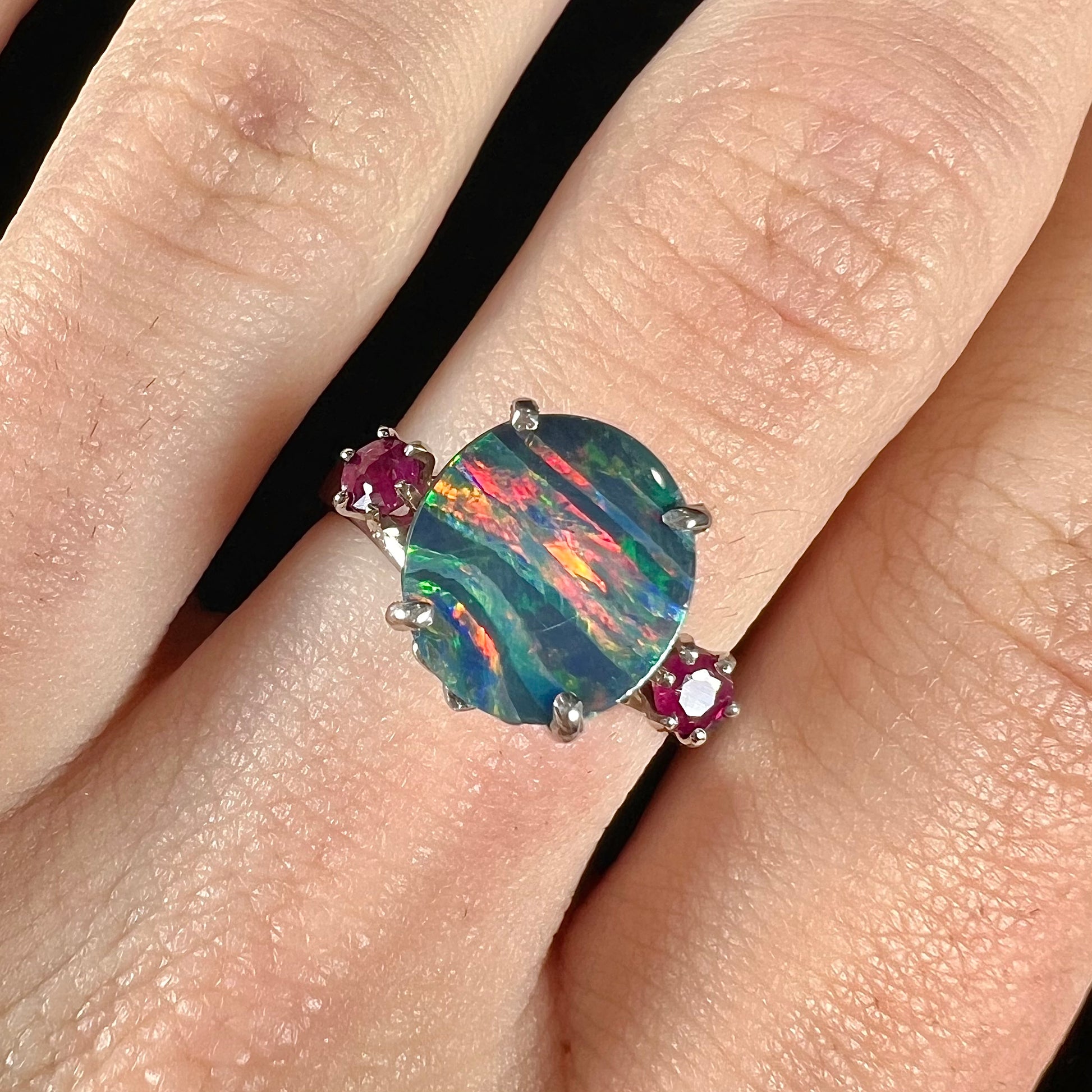 A ladies' 14kt white gold Australian black boulder opal doublet ring set with two round cut rubies.