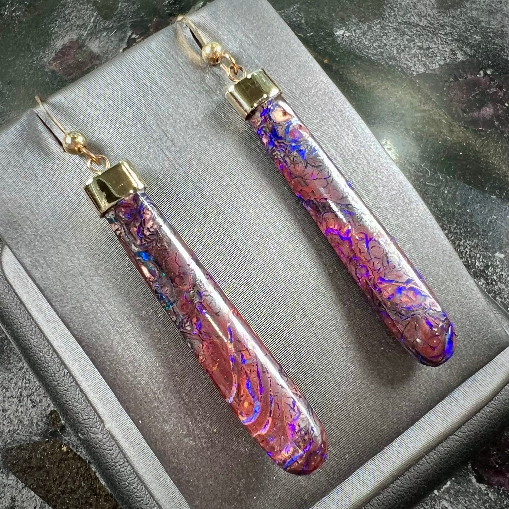 A pair of yellow gold cap Koroit boulder opal dangle earrings.  Purple highlights are seen.