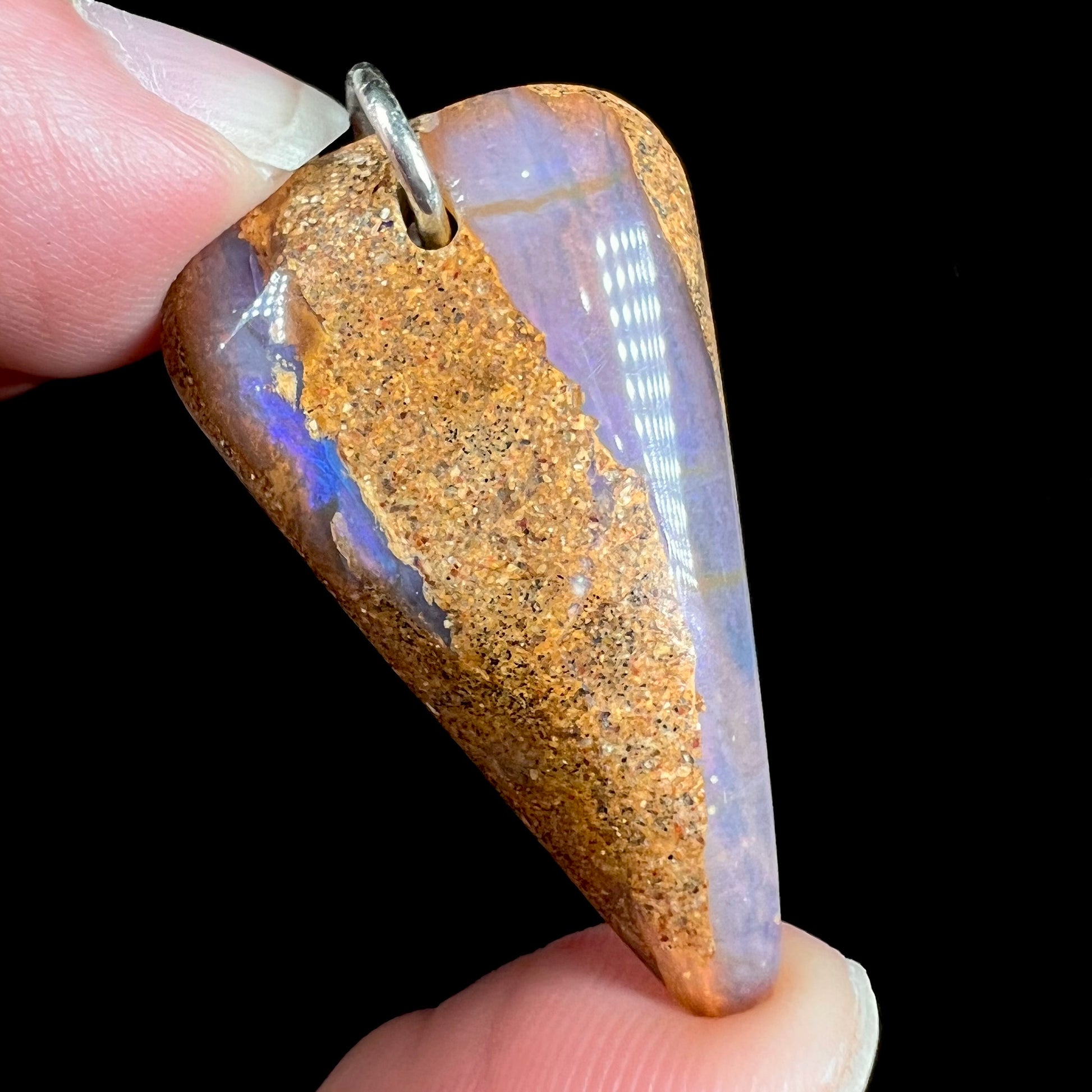 A drilled boulder opal stone with a sterling silver ring through the hole to be worn as a pendant.